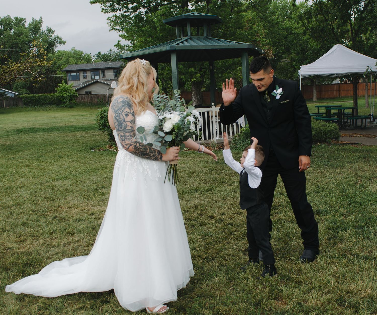 An outdoor wedding scene with a white dress against green grass and trees.