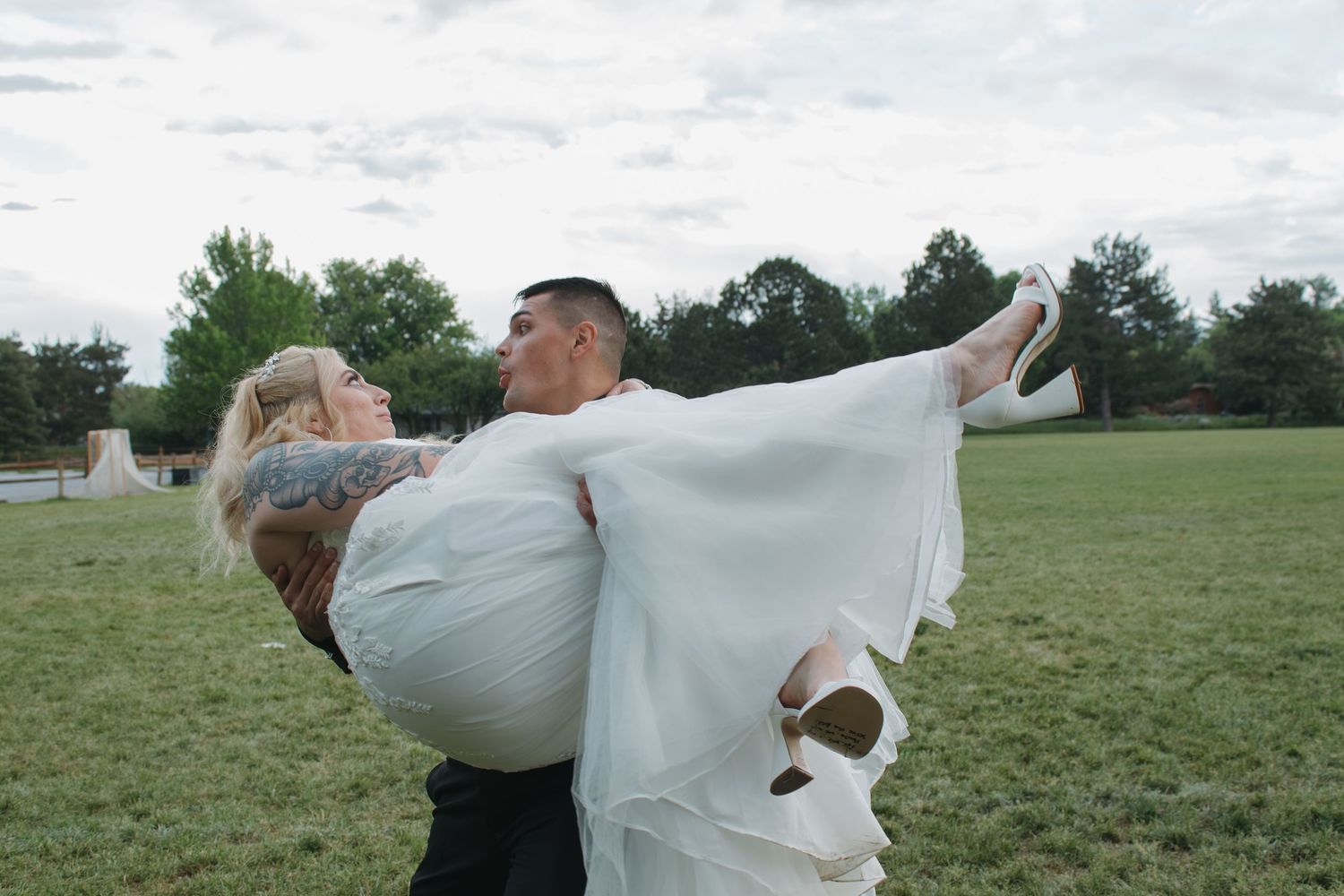 Couple embraces in a grassy field under cloudy skies in a romantic wedding photoshoot sequence.