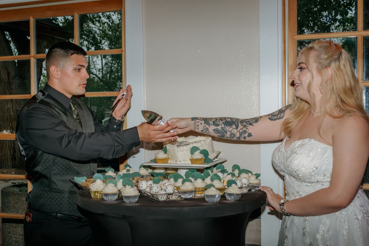Wedding dessert table decorated with eucalyptus leaves and various treats.