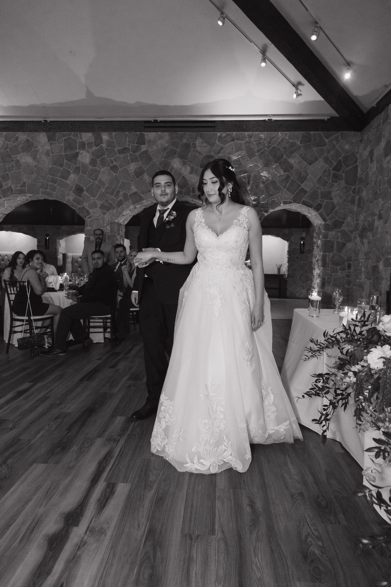 Bride and groom making grand entrance at wedding reception in black and white.