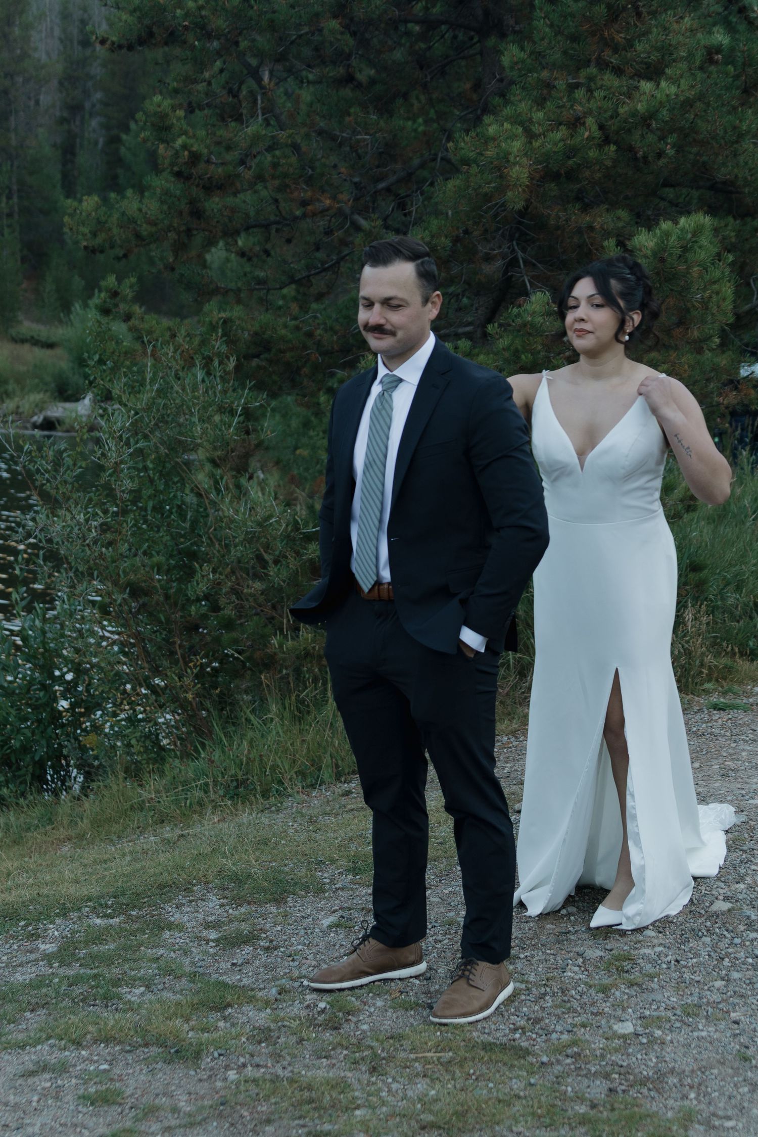 A couple poses on a rocky path surrounded by lush greenery at an outdoor wedding photoshoot.