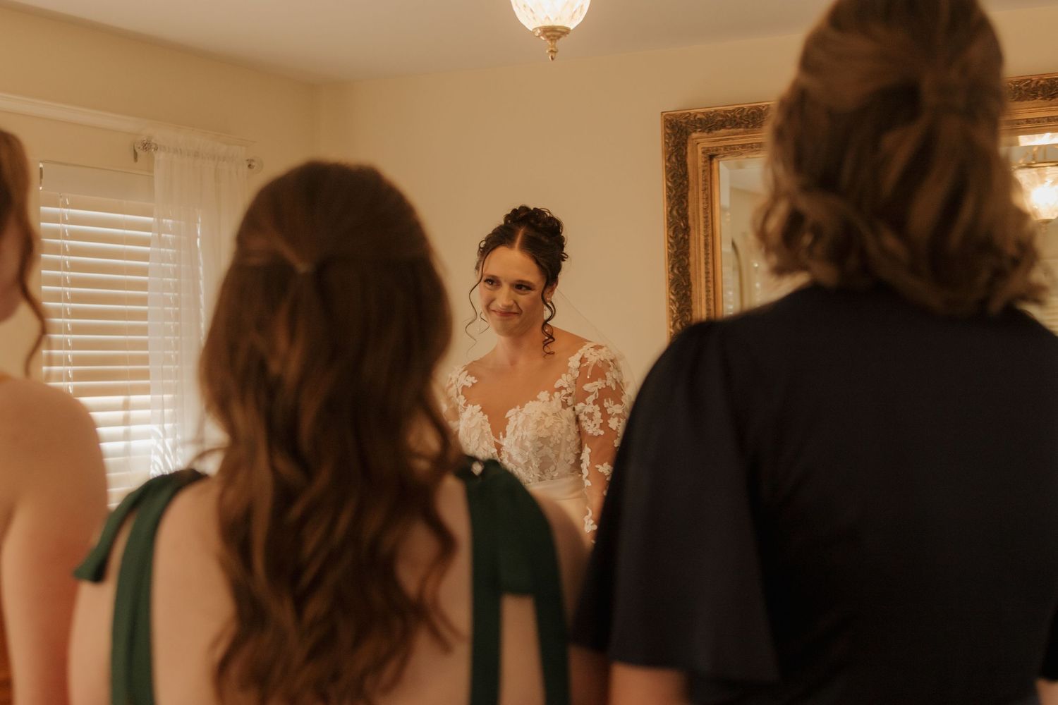 Bridesmaids and bride preparing together in a warmly lit room with window light.