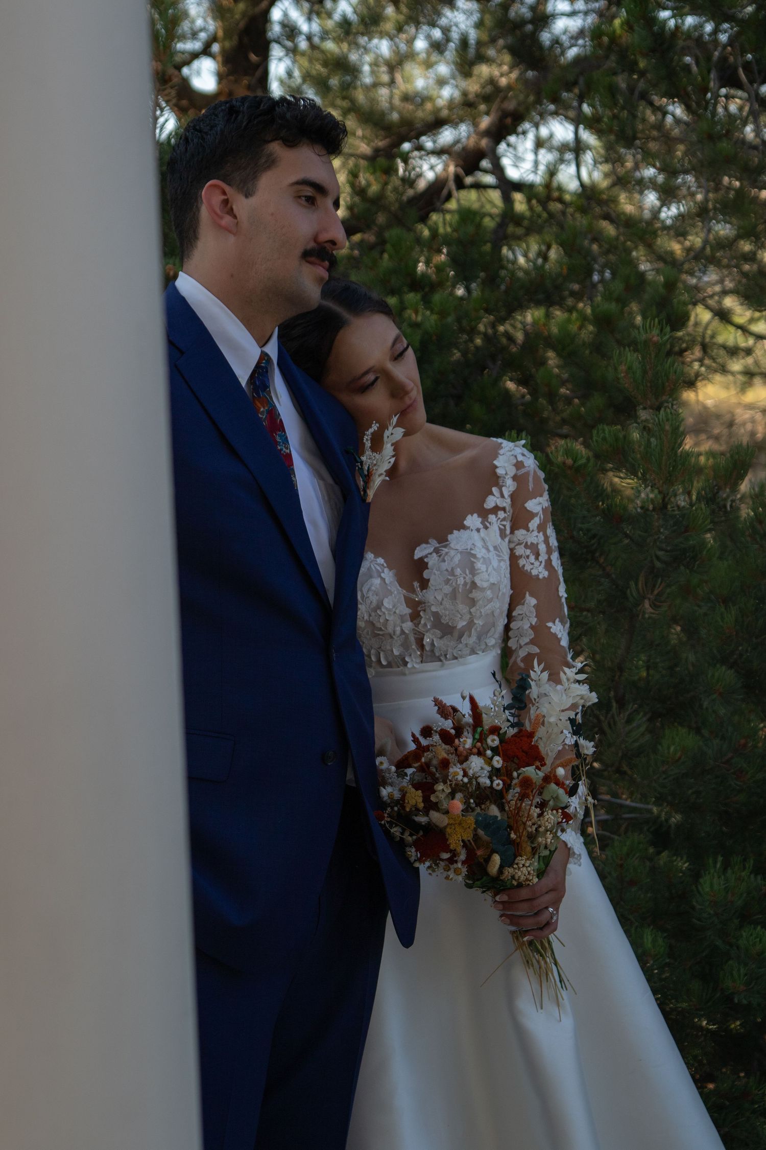 Romantic outdoor portrait with autumn wedding bouquet featuring dried flowers.