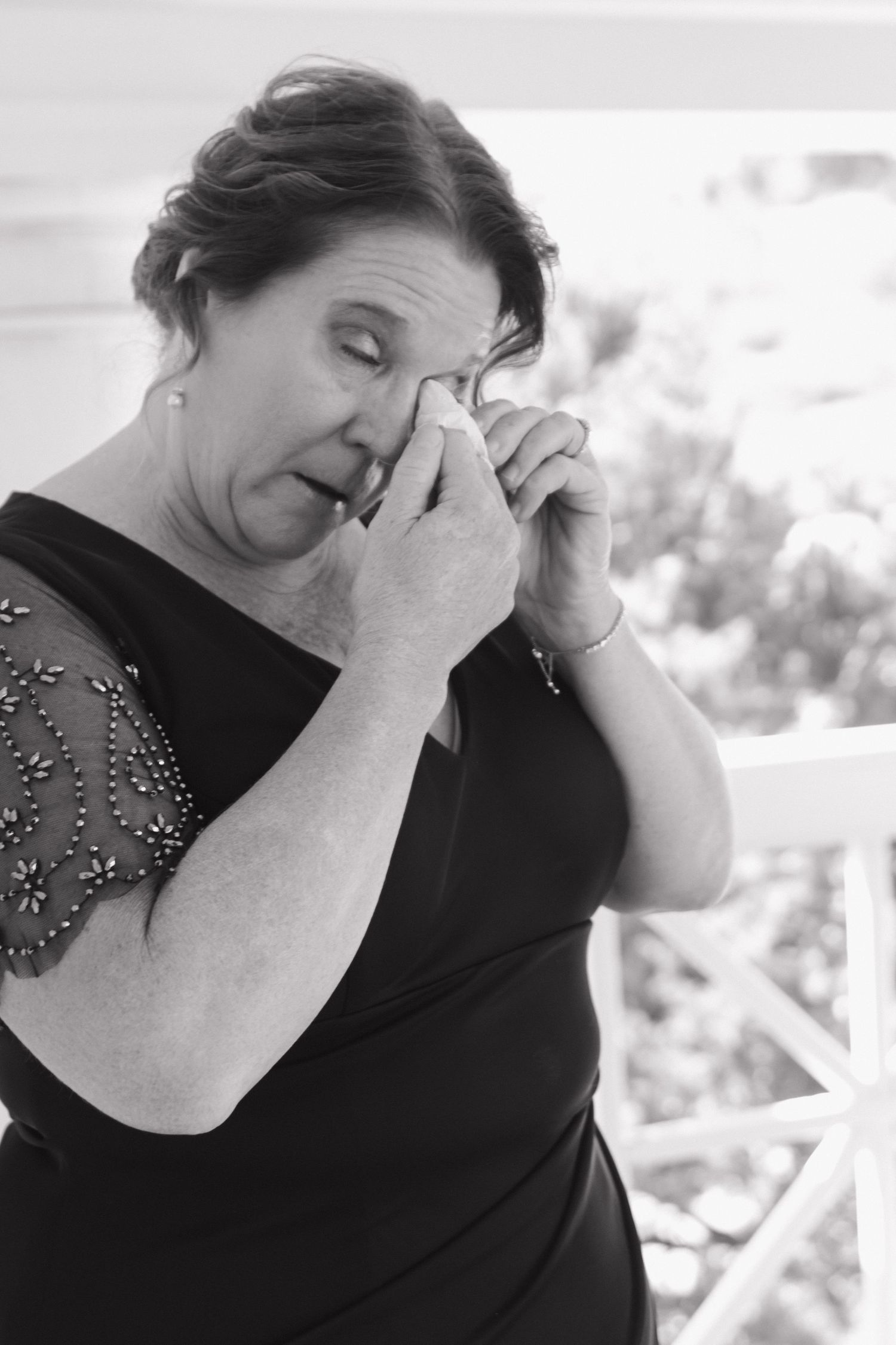 Person in black dress shows emotional reaction during wedding moment.