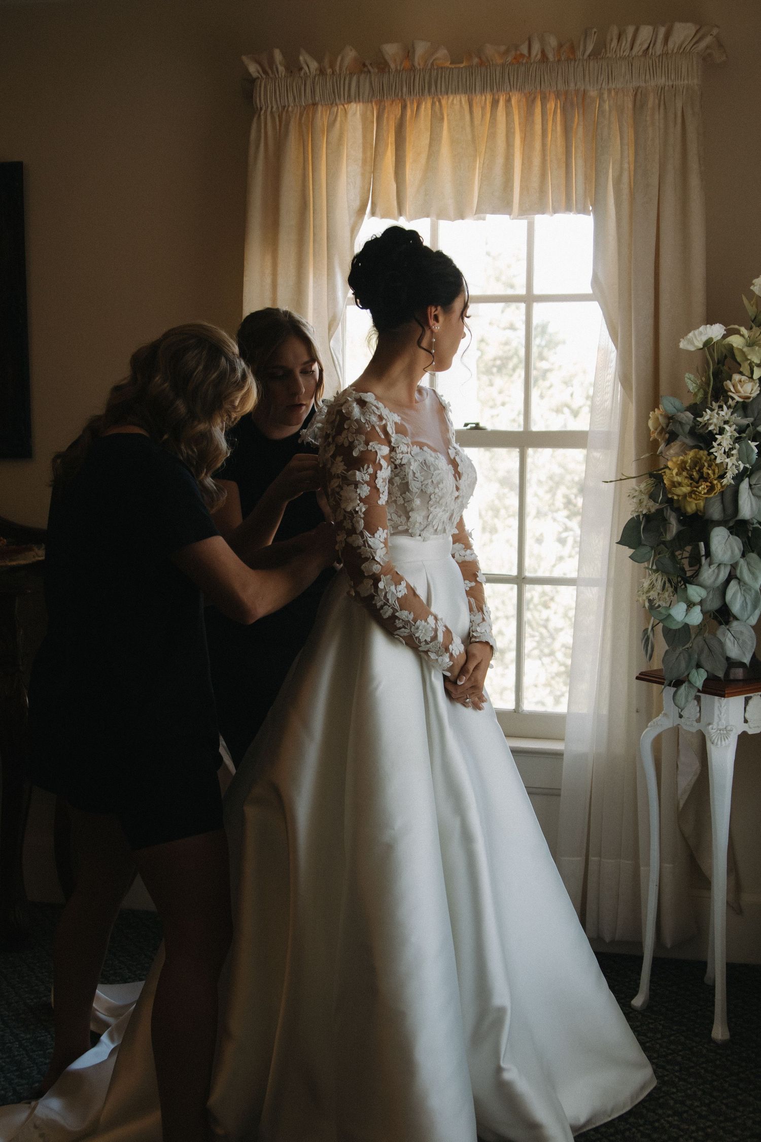 Bridal preparations taking place in a room decorated with white floral arrangements.