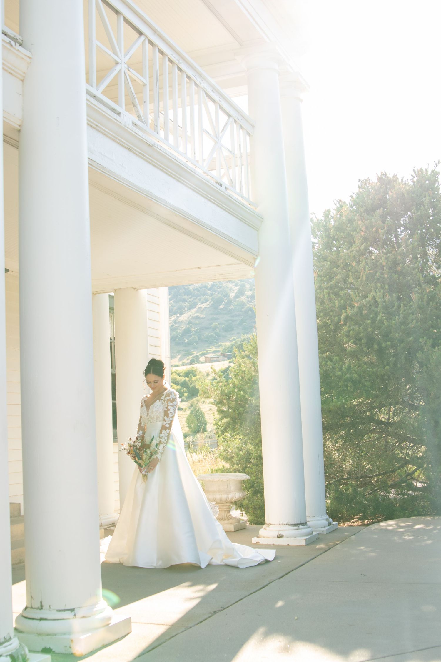 Wedding photos being taken on a white columned porch with mountain views in the background.