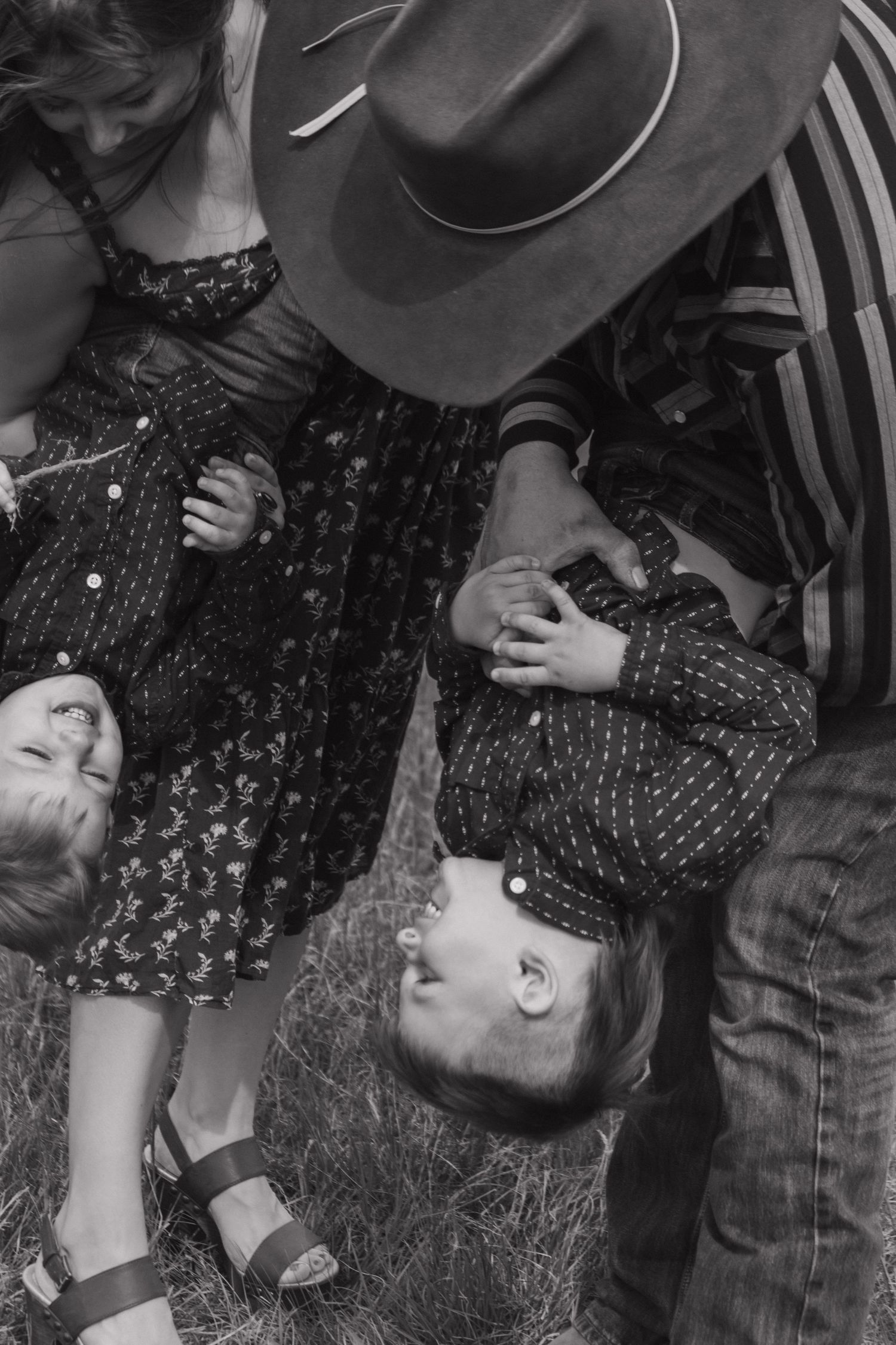 Black and white portrait of family playing and laughing together outdoors.