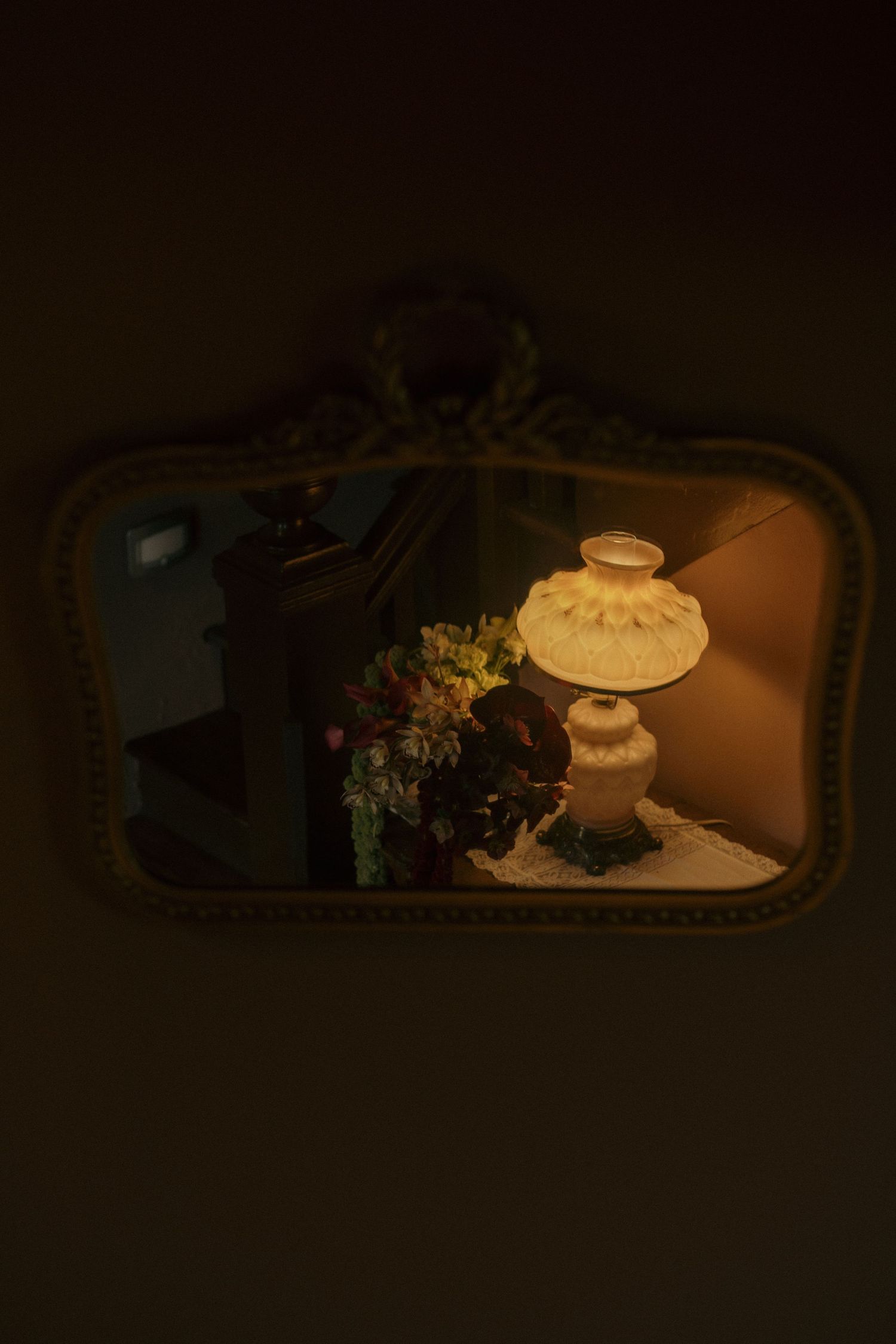 Vintage mirror reflection showing wedding cake and floral decorations in dim lighting.
