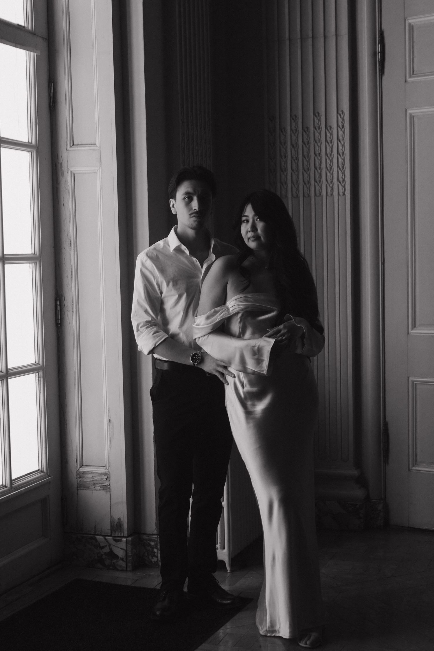 Black and white series of romantic dance poses in an elegant hallway with large windows.