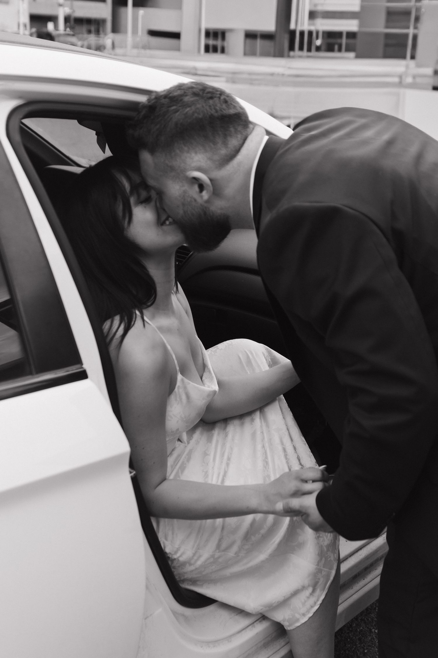 Black and white photo of couple by car door.