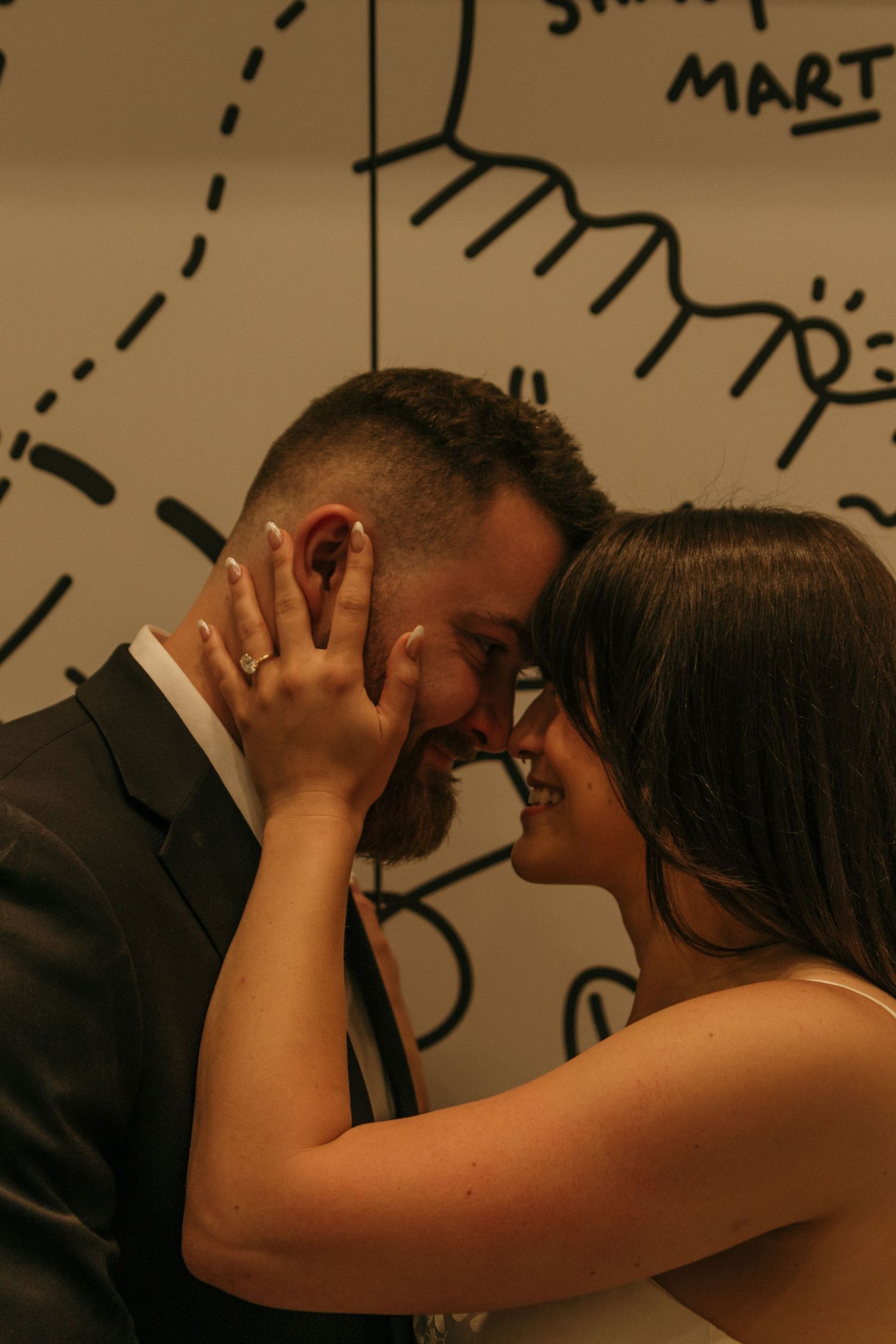 Two dancers move closely together against a wall with handwritten text in the background.