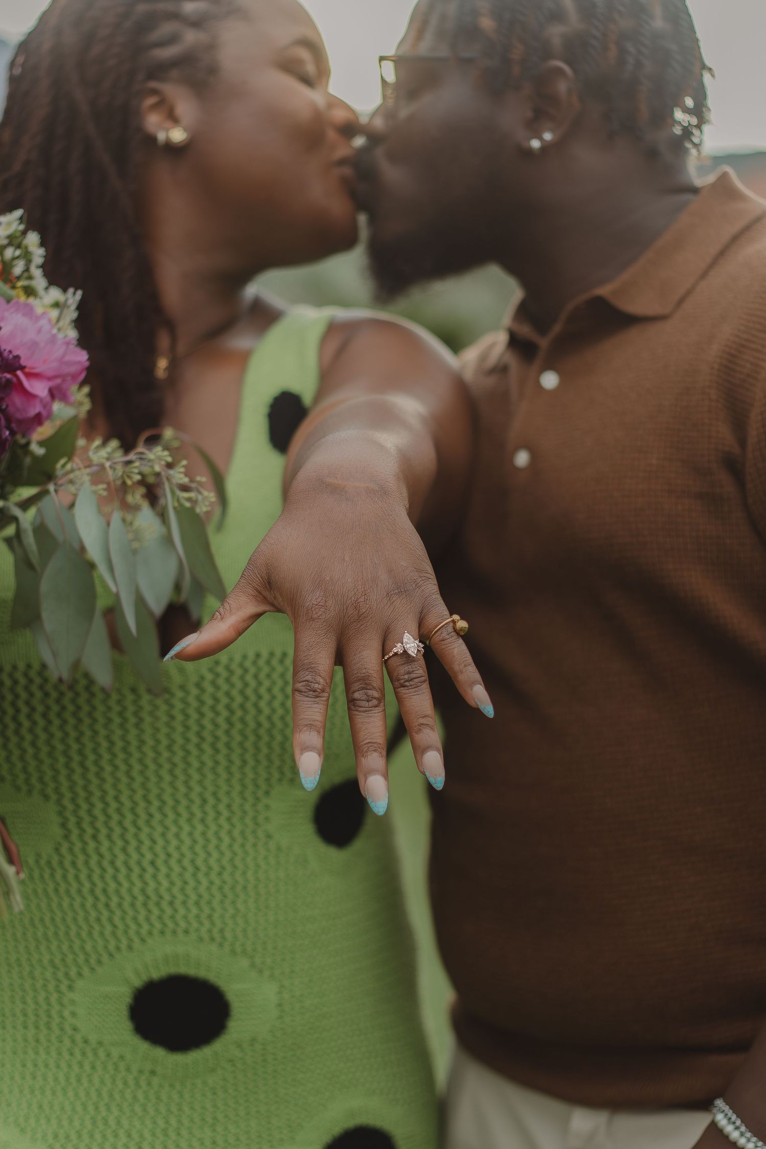Close-up of an engagement ring while a couple shares an intimate moment in front of a mountain landscape.