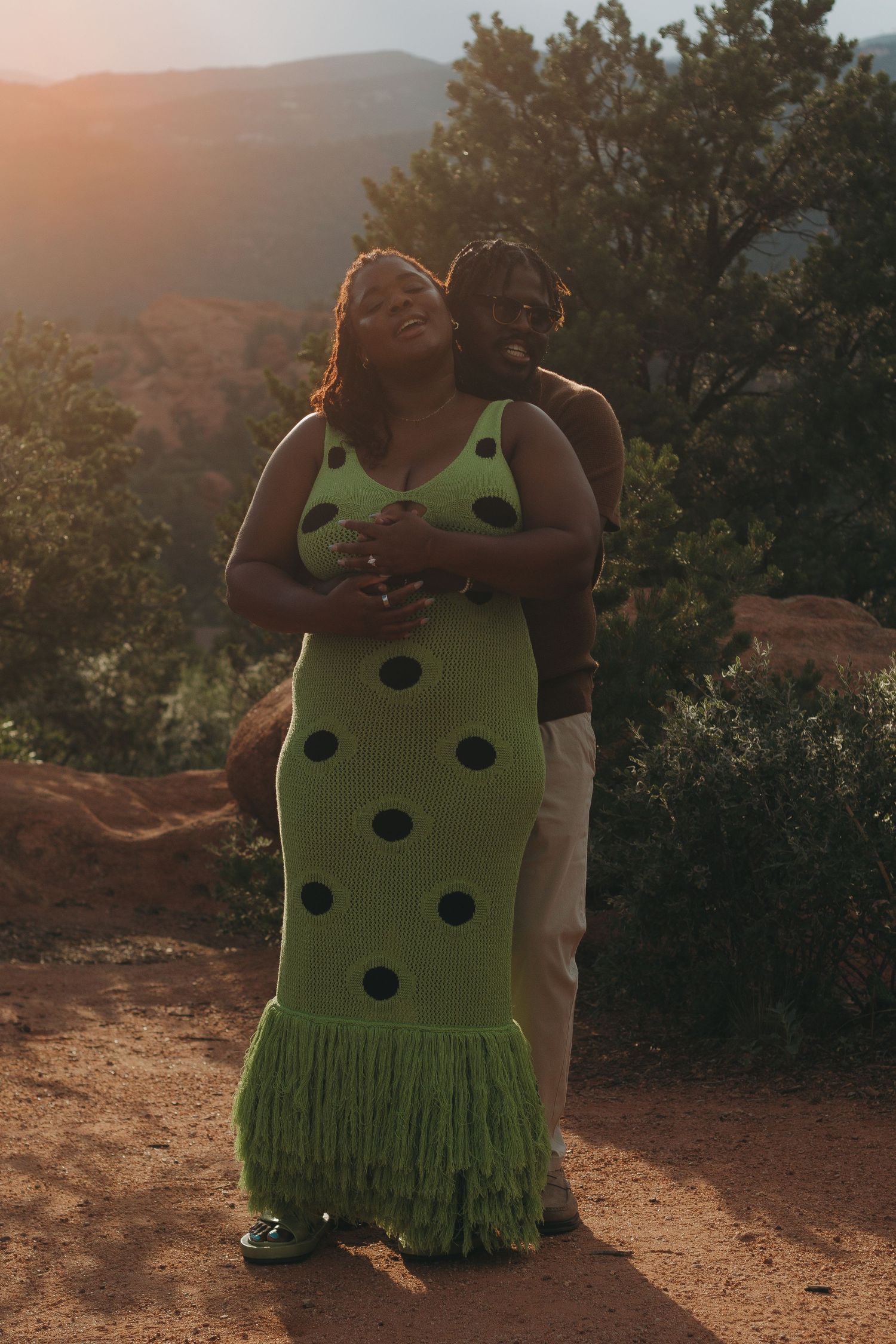 A couple shares an intimate moment on a dusty trail at sunset.