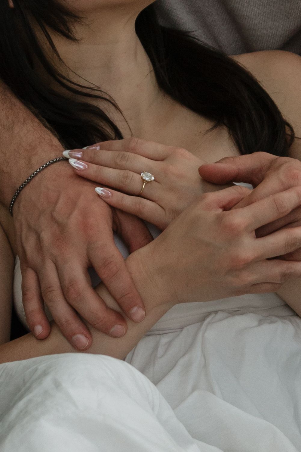 Close-up shot of hands with an engagement ring showing an intimate moment.