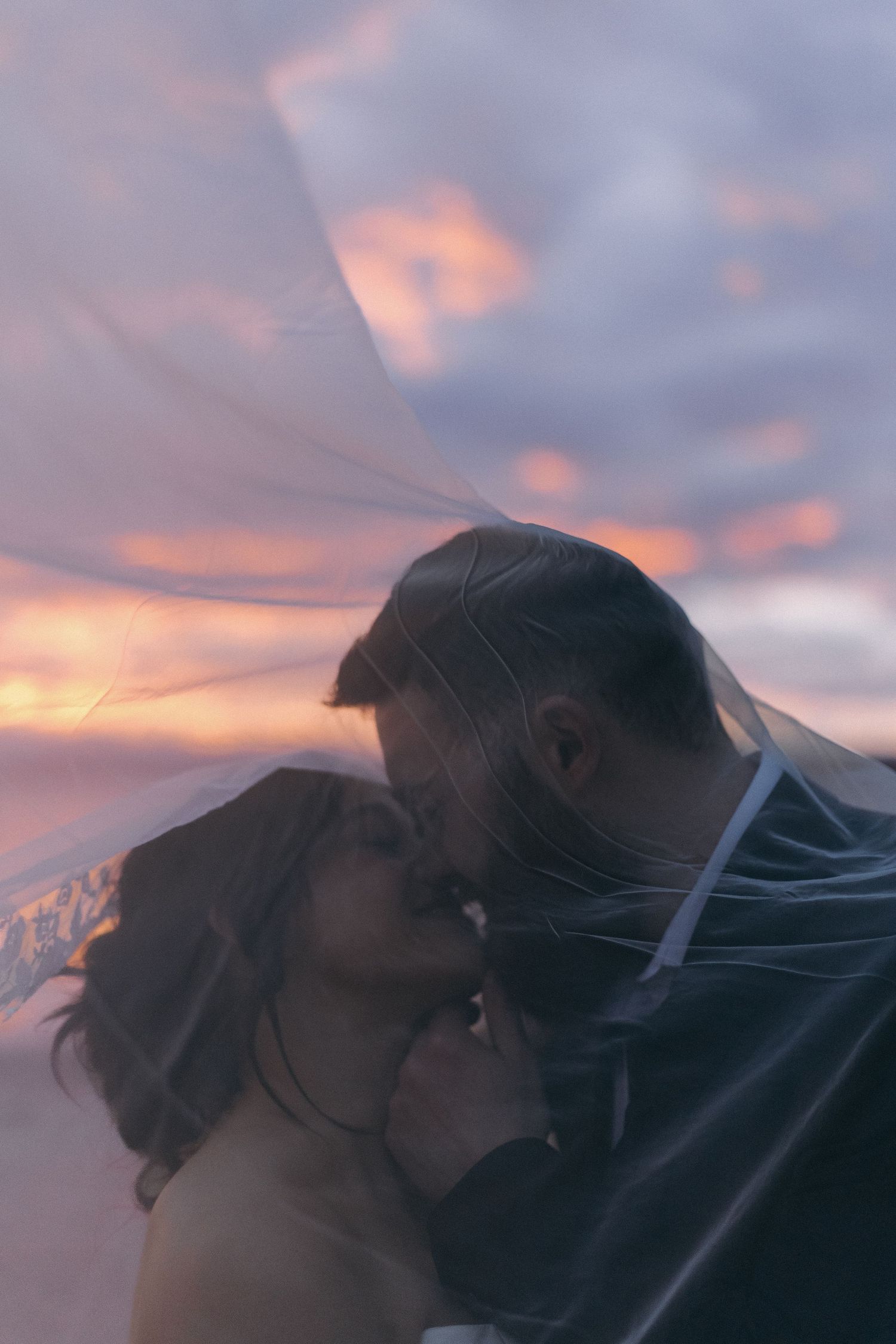 Romantic silhouettes against a sunset sky with soft pink and purple hues.