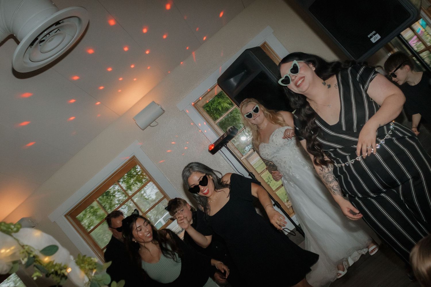 People dancing and socializing at an indoor party with red lighting effects.