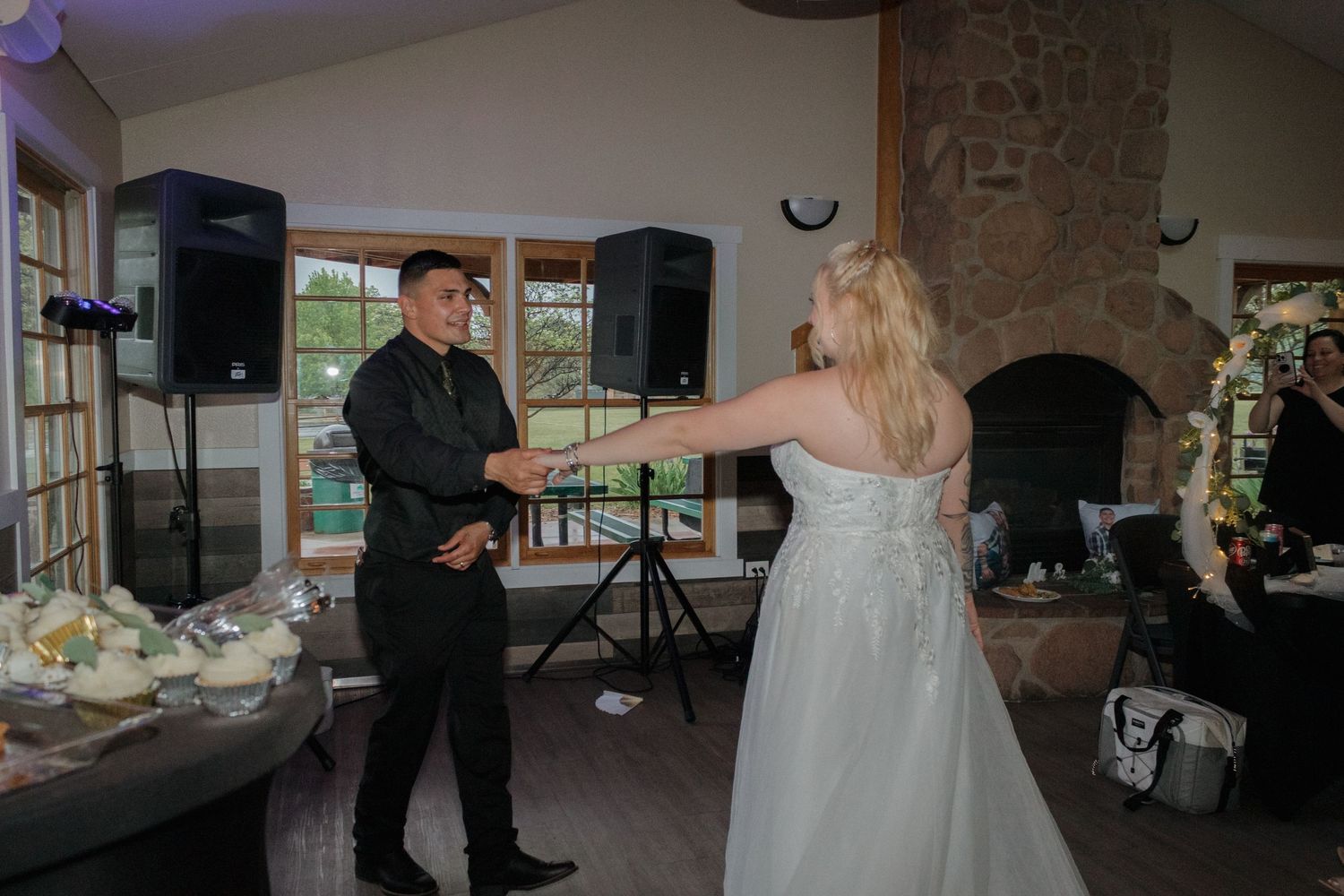 A couple shares an intimate dance moment in a rustic indoor wedding venue with stone walls.