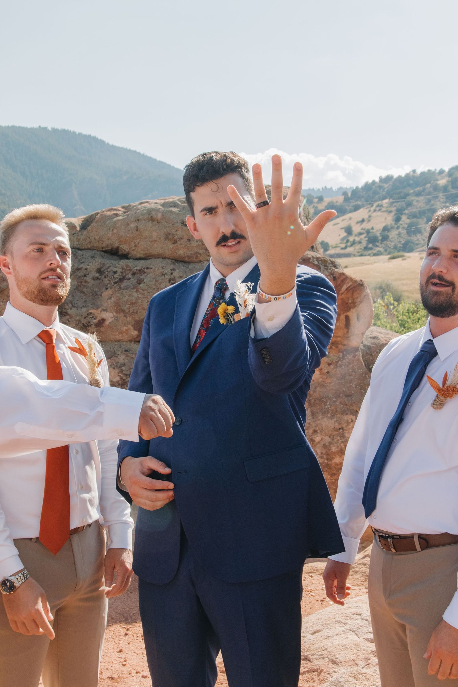 Groomsmen in navy suits and khakis posing informally during outdoor wedding photos.