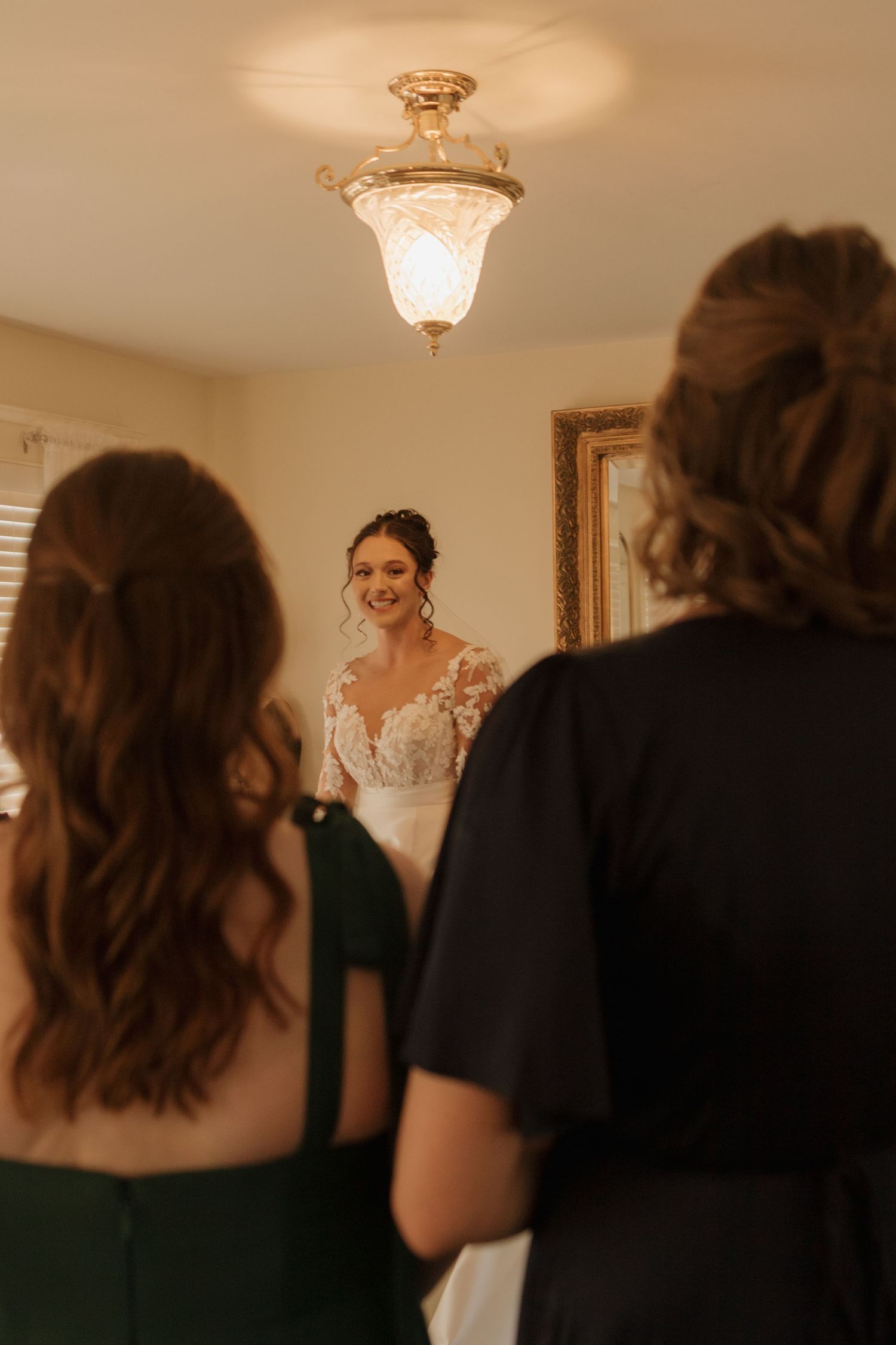 Blurred silhouettes of people helping with wedding preparations in a sunlit room.