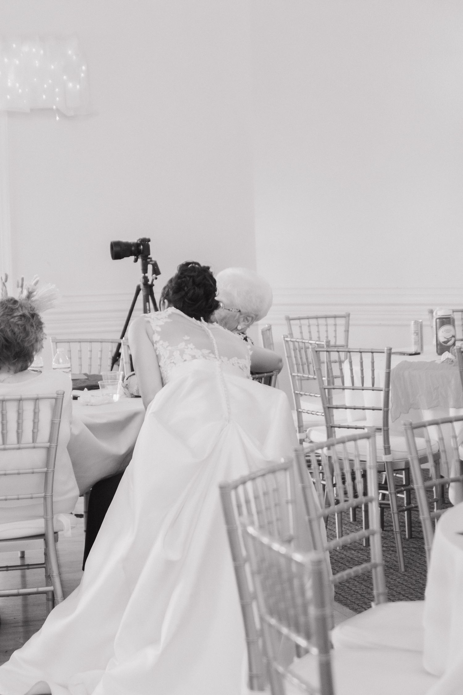 White wedding dress detail shown against elegant chiavari chairs at reception venue.