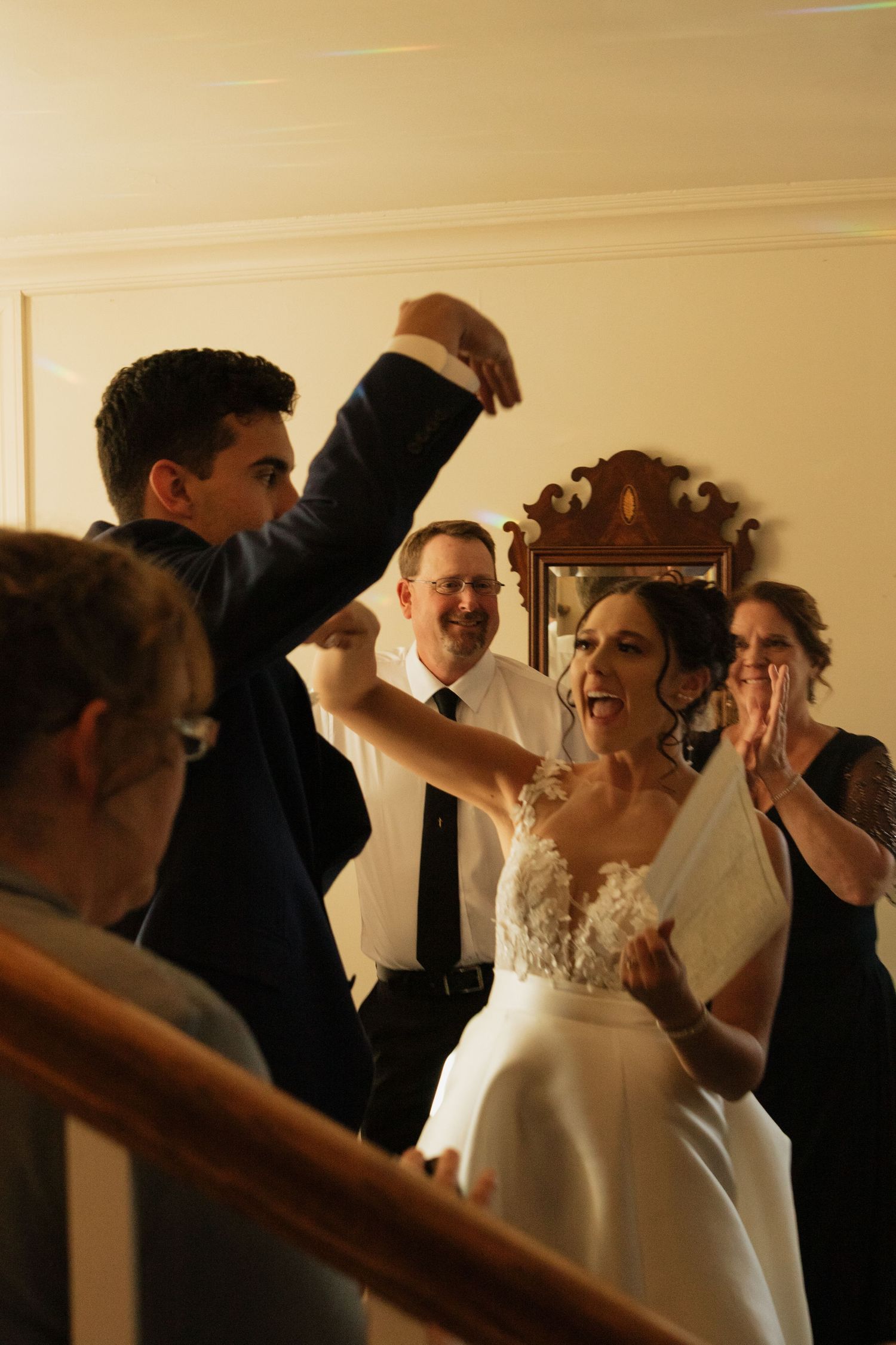 Joyful wedding celebration moment captured in warm golden light indoors.
