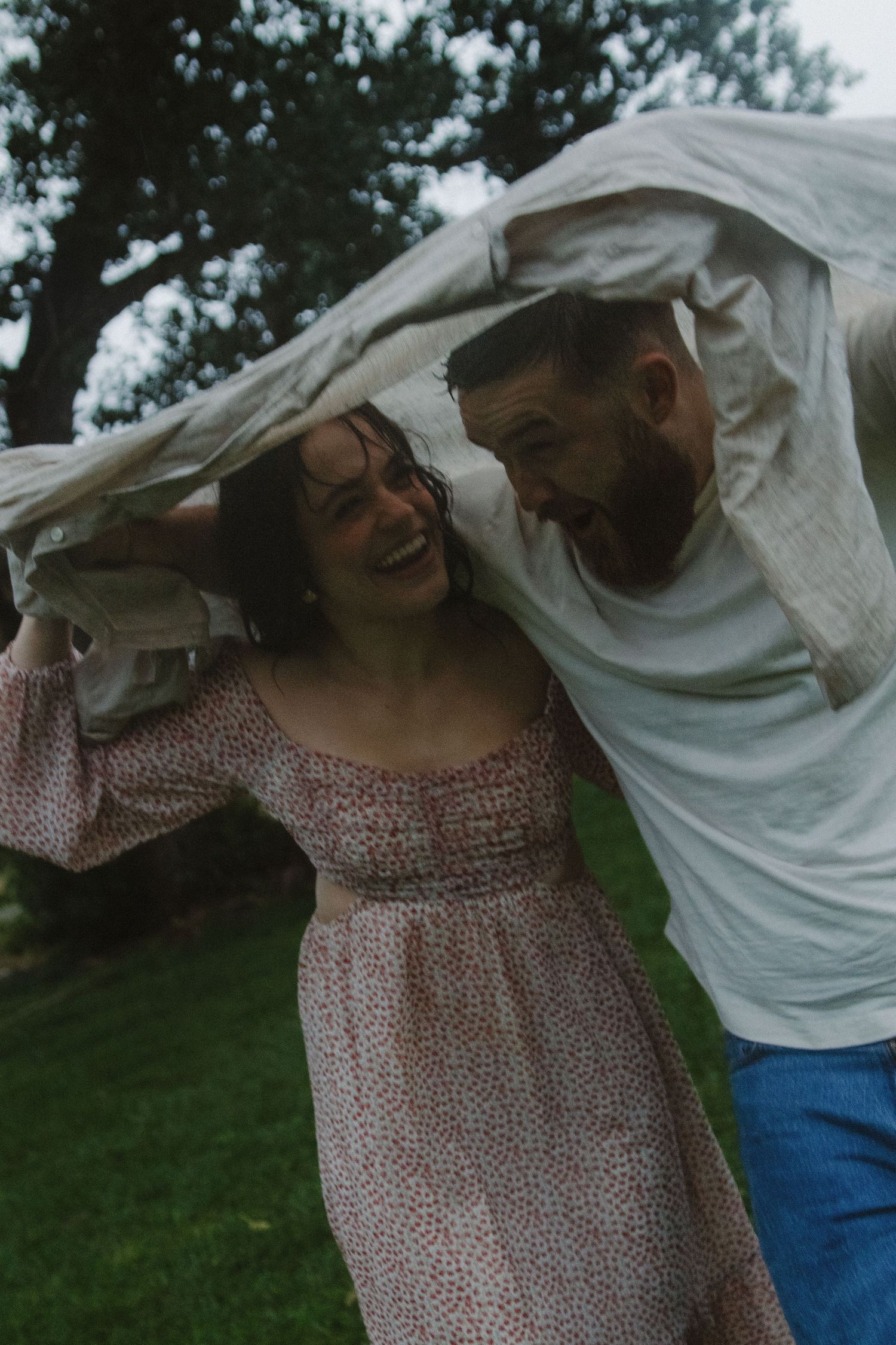 Couple in casual attire sharing joyful moments outdoors with animated expressions.
