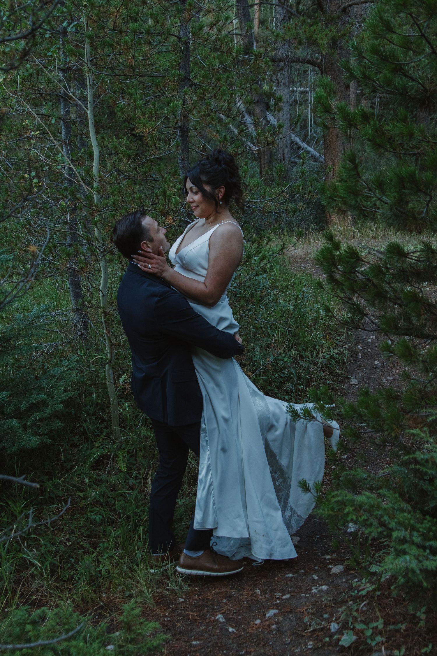 A romantic wedding moment captured in a lush forest setting at dusk.