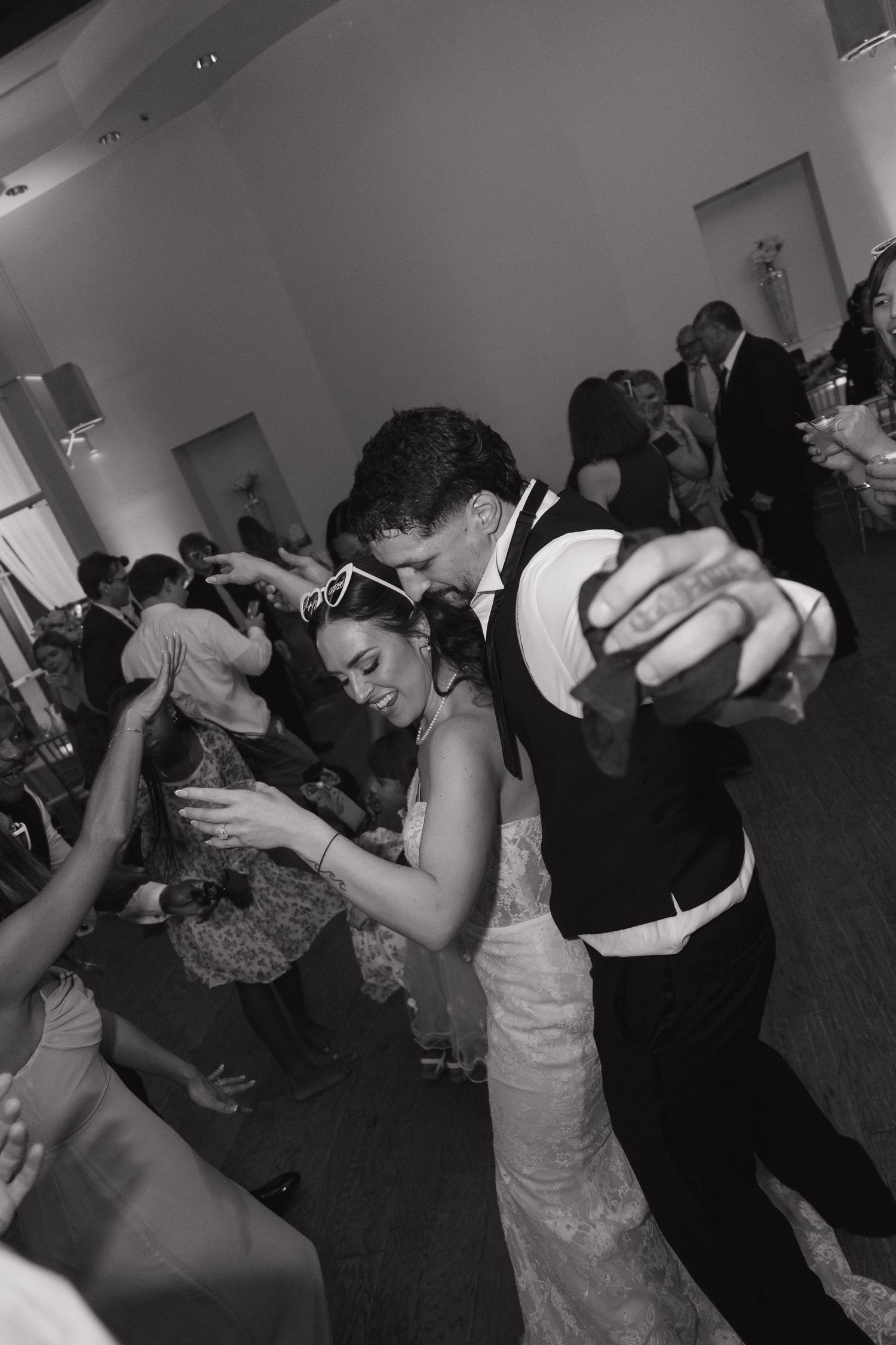 Black and white photo of bride and groom sharing a fun dance moment at their wedding reception.