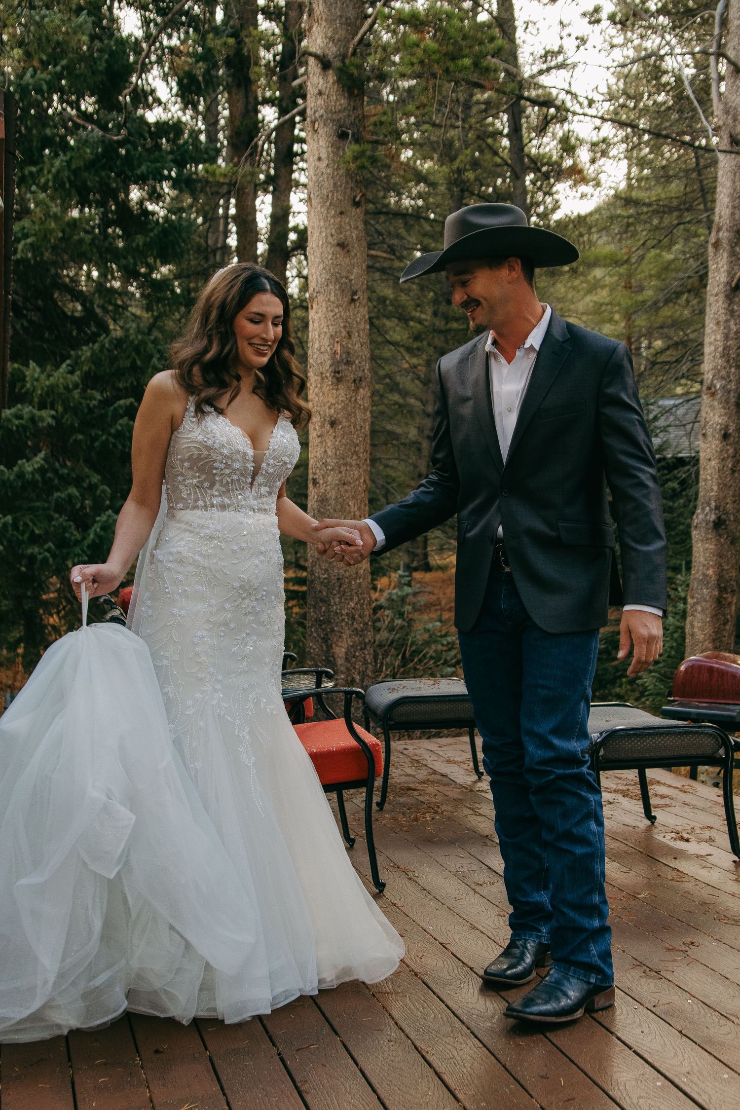 Couple dancing together on wooden deck with forest backdrop.