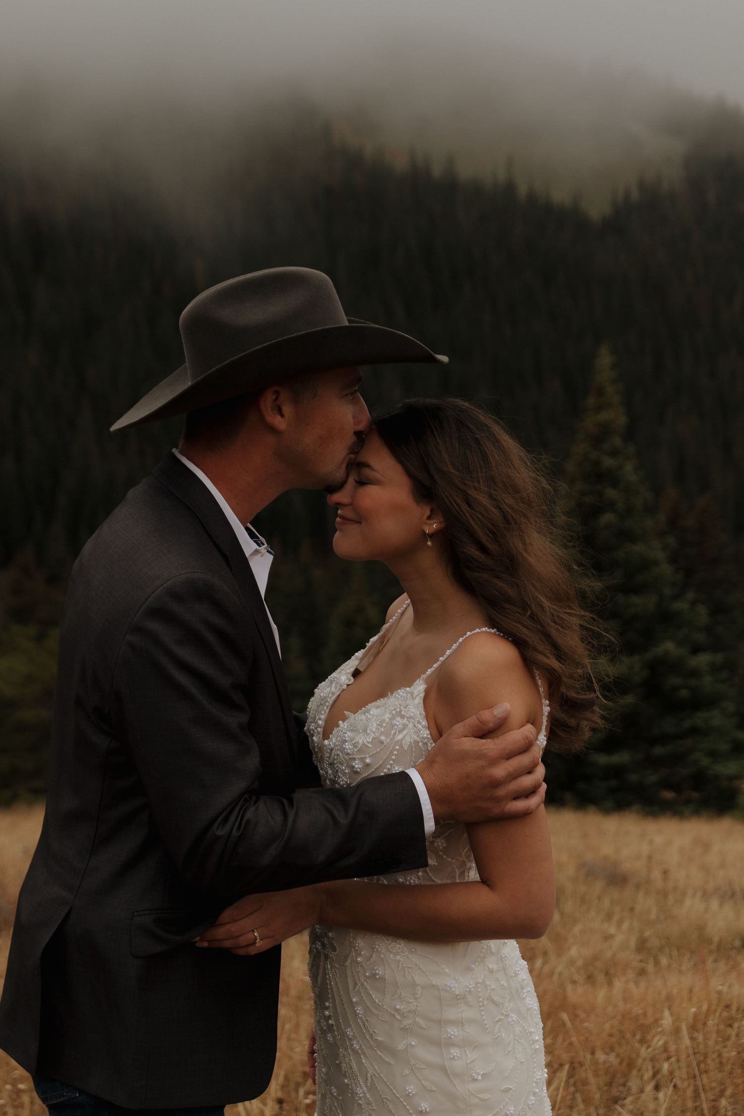 A romantic moment between newlyweds against a misty mountain backdrop.