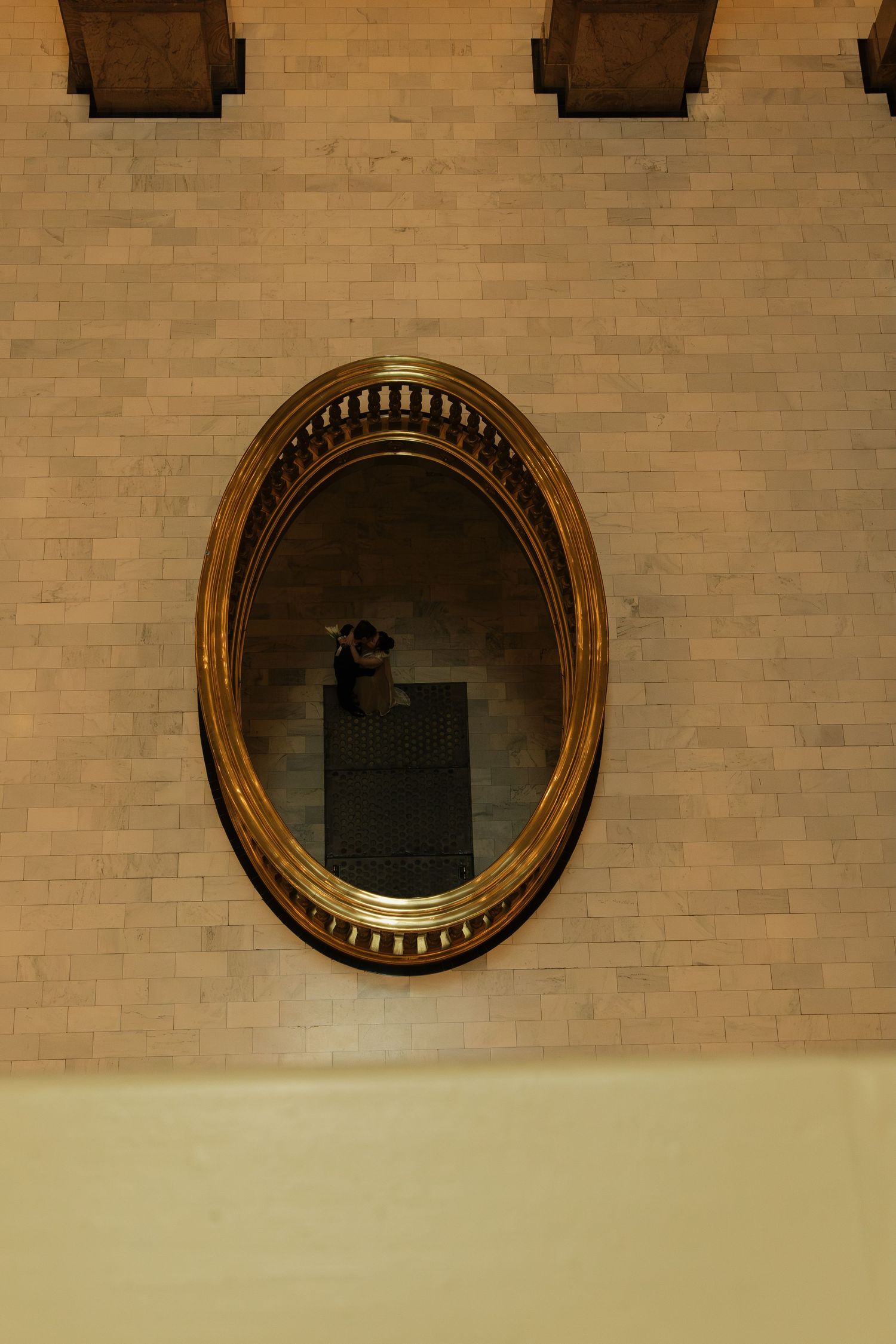 Row of decorative round gold mirrors mounted on beige brick wall.