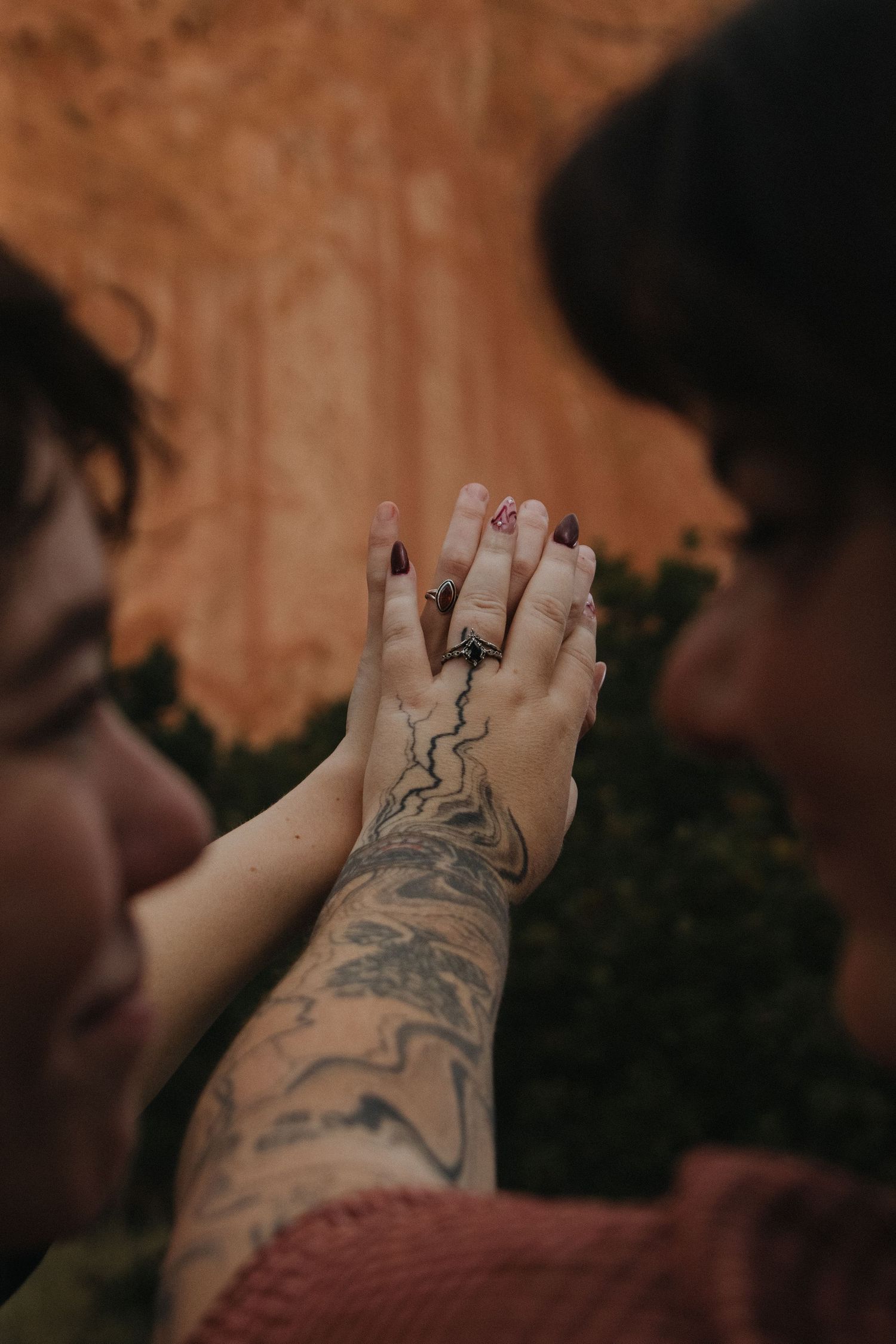 Close-up sequence of a tattooed foot with dark nail polish against a blurred orange background.