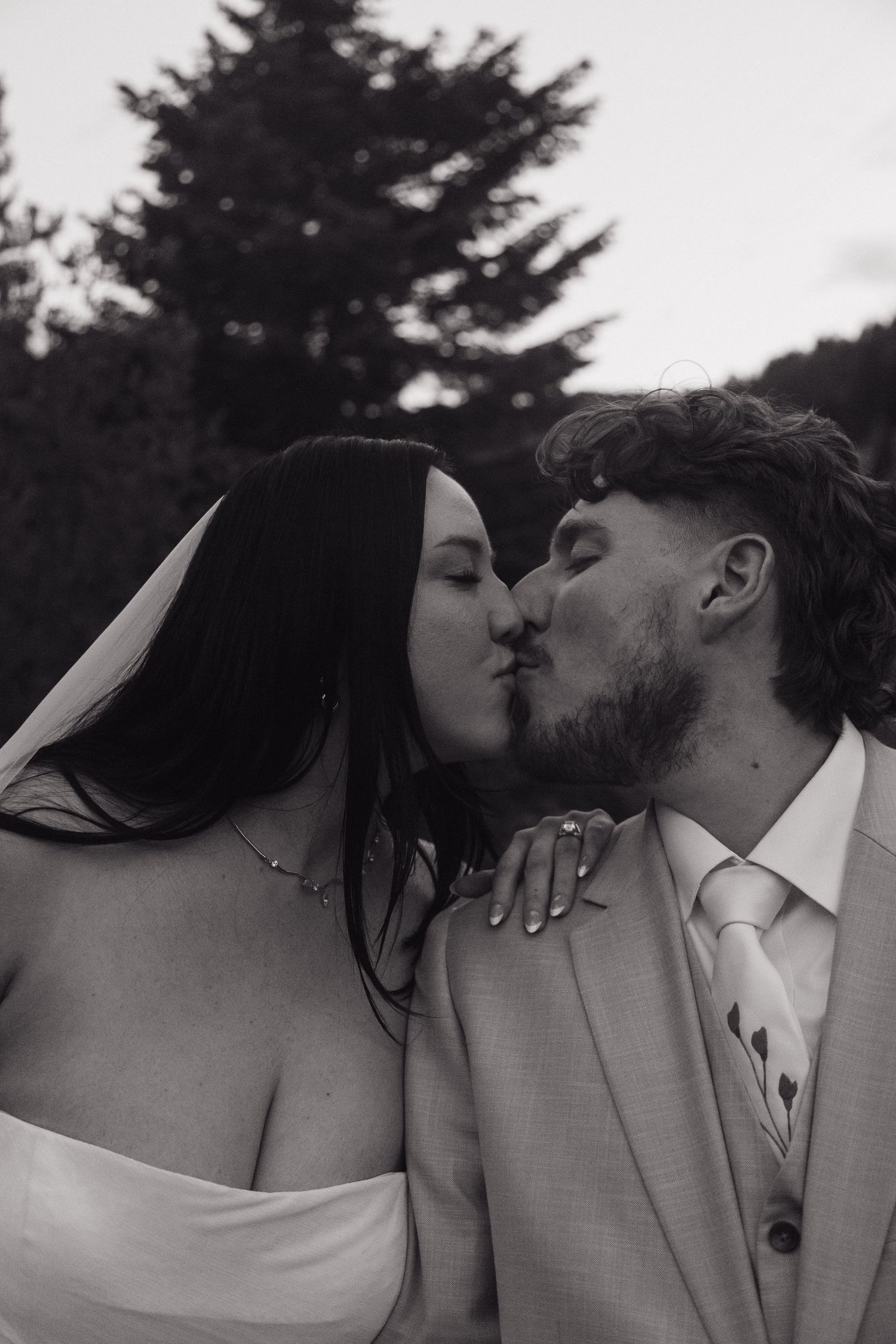 Black and white close-up of bride and groom sharing a tender kiss during their outdoor wedding.