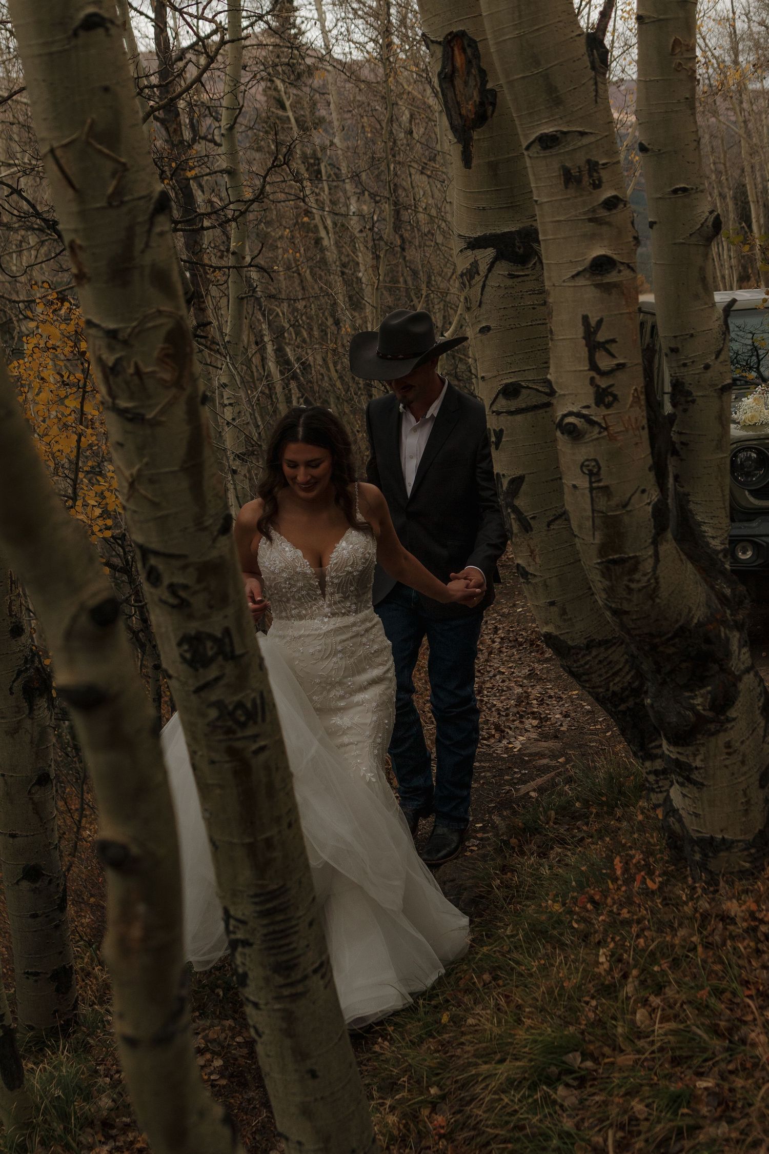 A couple shares an intimate moment among a grove of white birch trees in autumn.