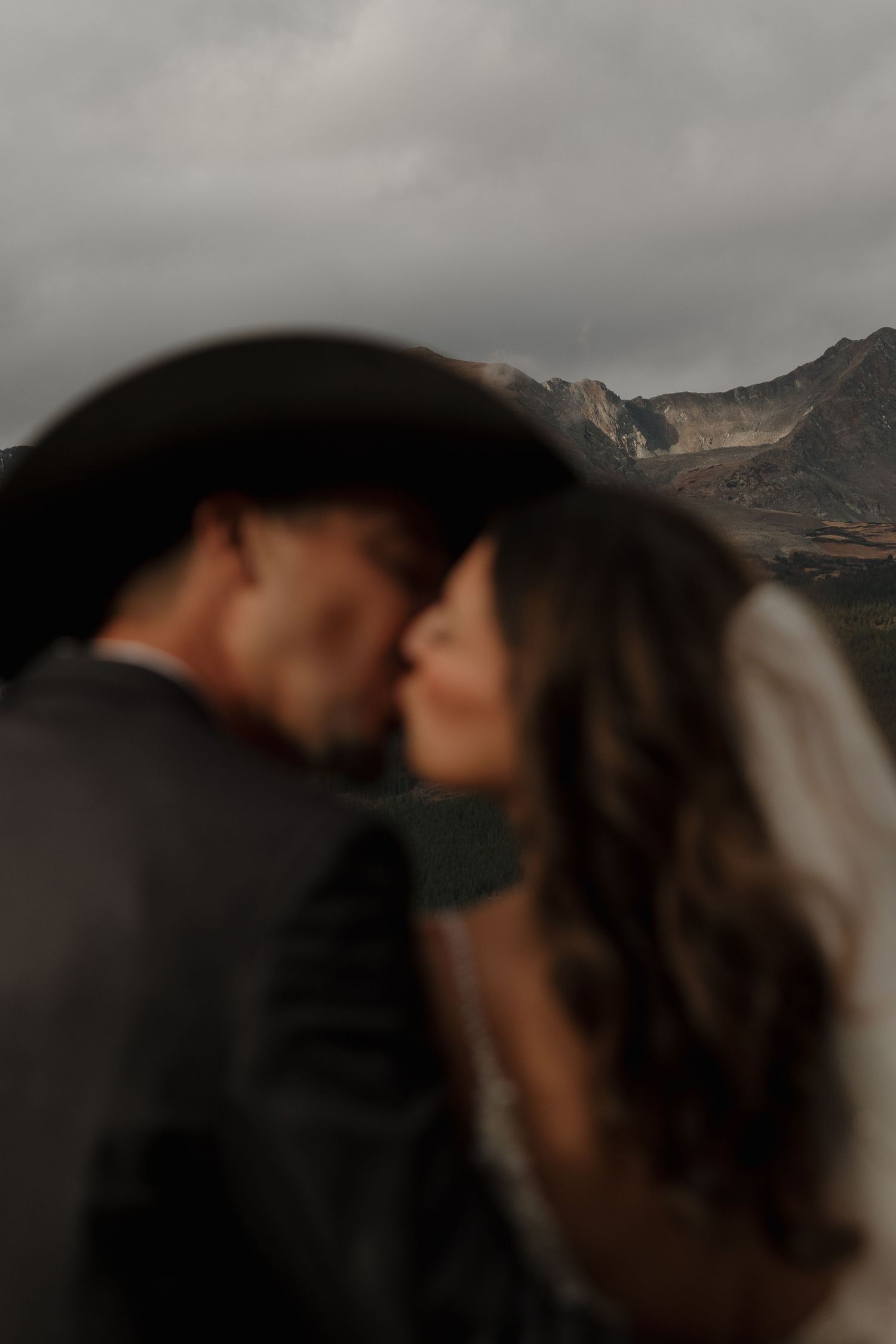 A silhouetted intimate moment with mountain peaks in the background.