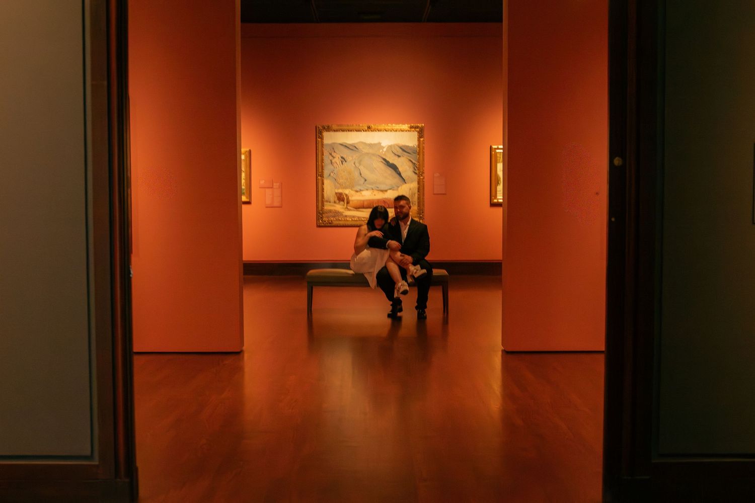 Orange-lit museum gallery with artwork displayed on walls.