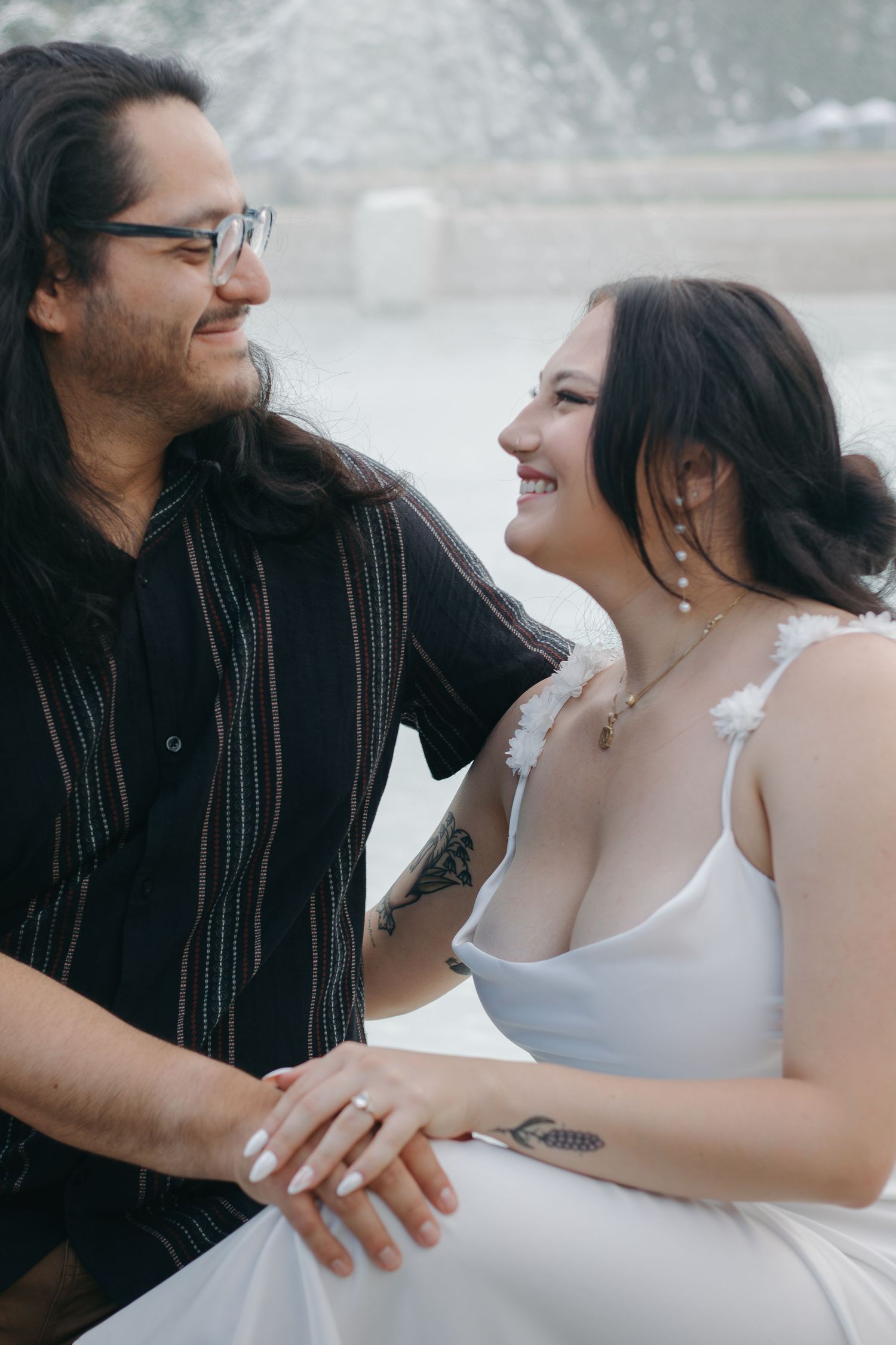 A romantic couple shares a joyful moment together outdoors, wearing contrasting black and white outfits.