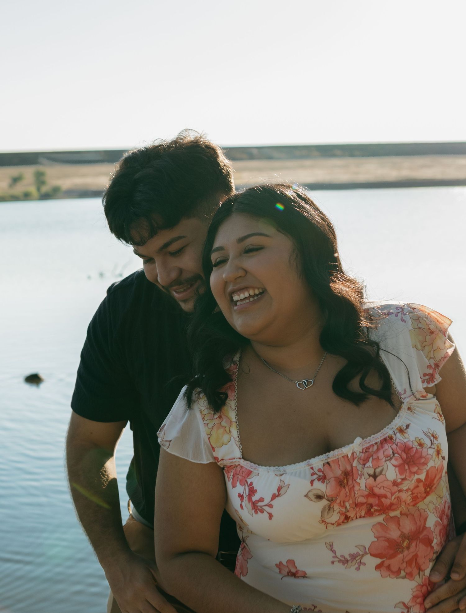 A joyful couple shares an intimate moment by the waterfront.