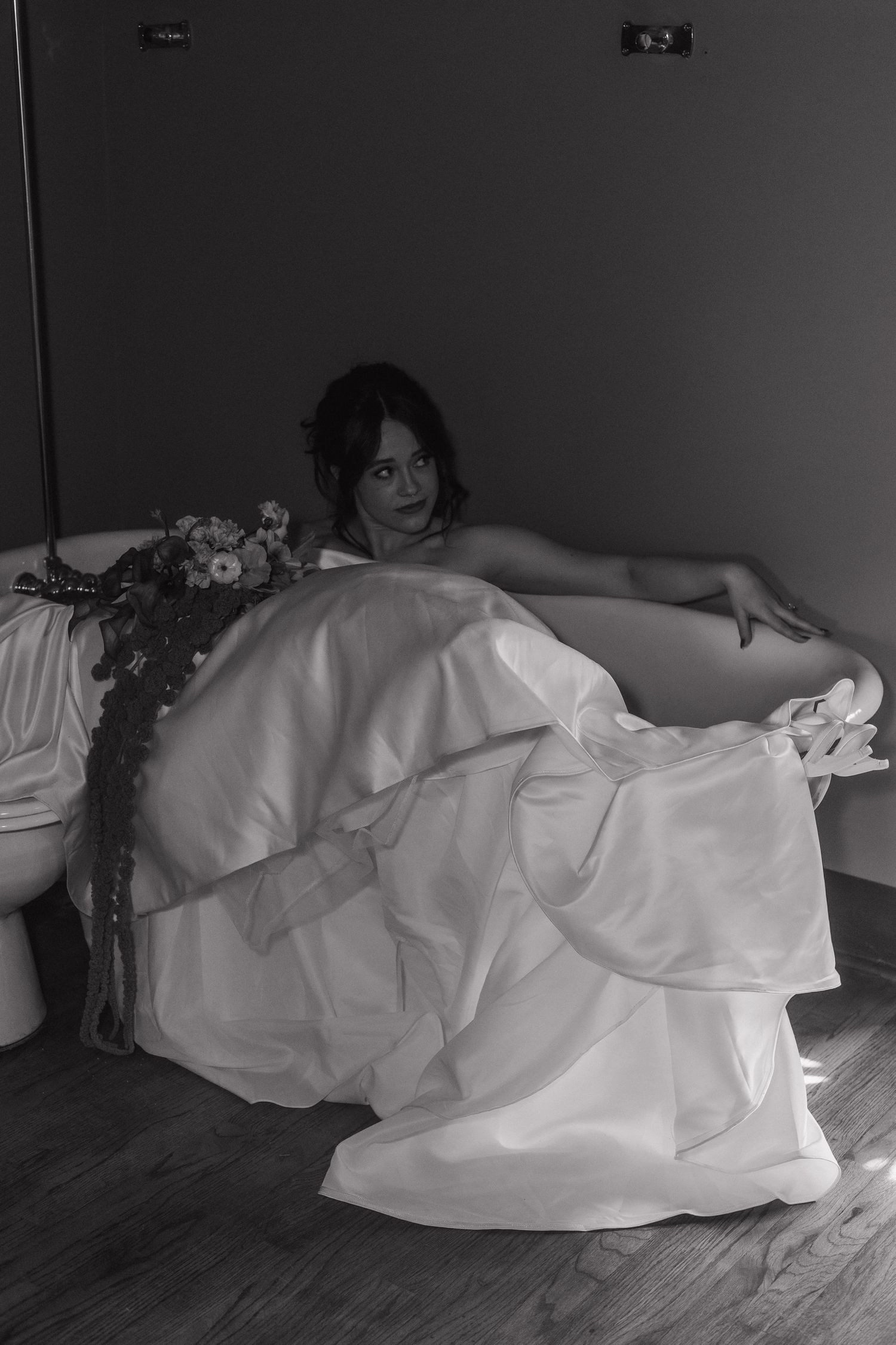 Artistic sequence of a flowing white wedding dress against dark floor in dramatic lighting.