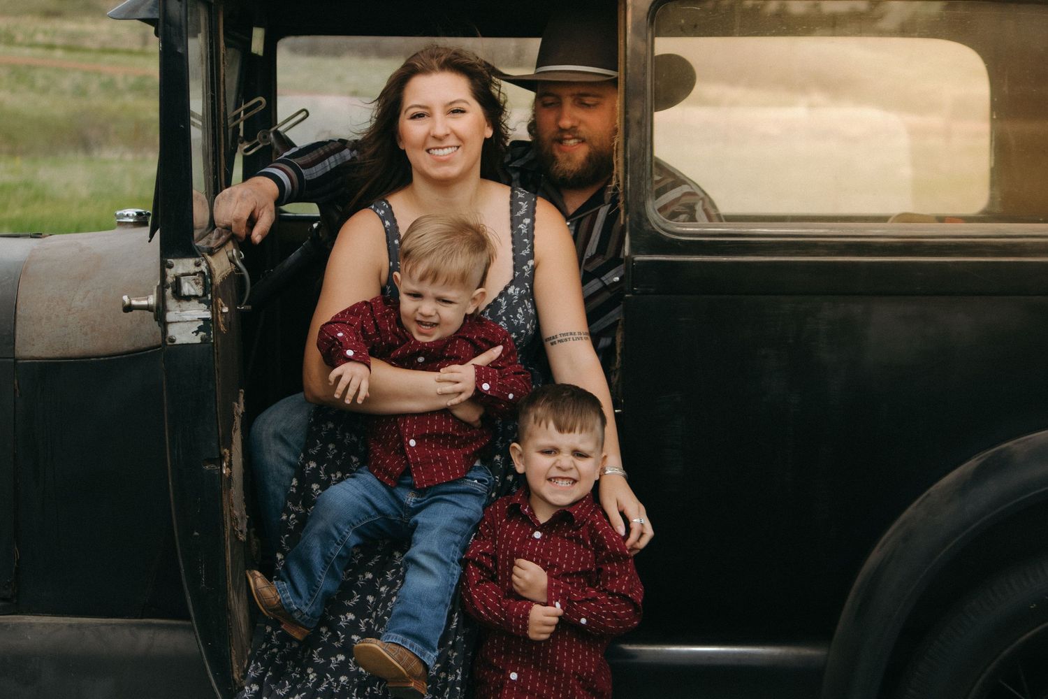 Family enjoying a candid moment together while seated in their classic car outdoors.