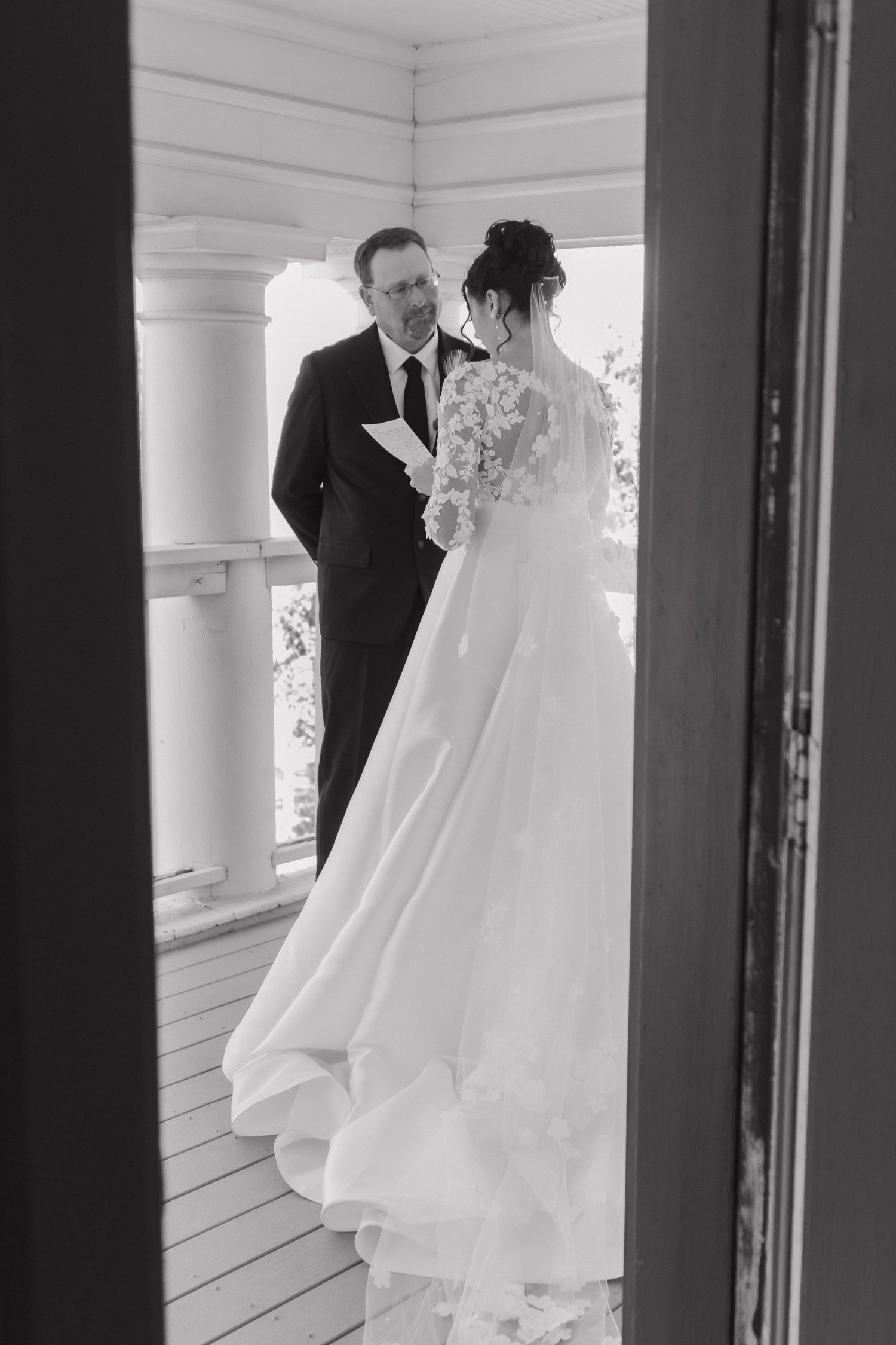 Black and white wedding photograph capturing first look moment on porch.