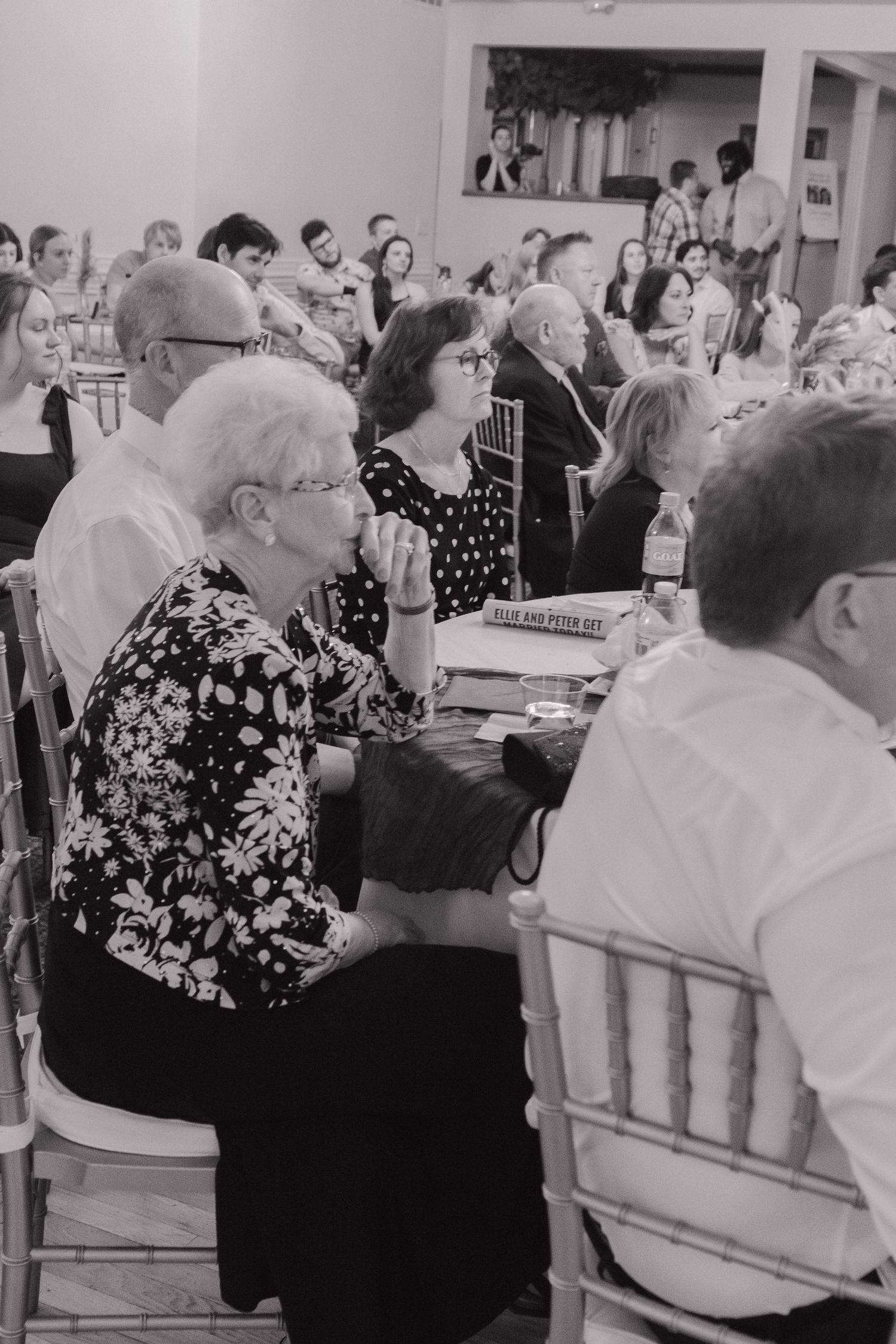Wedding reception guests seated at tables in a banquet hall during celebration.