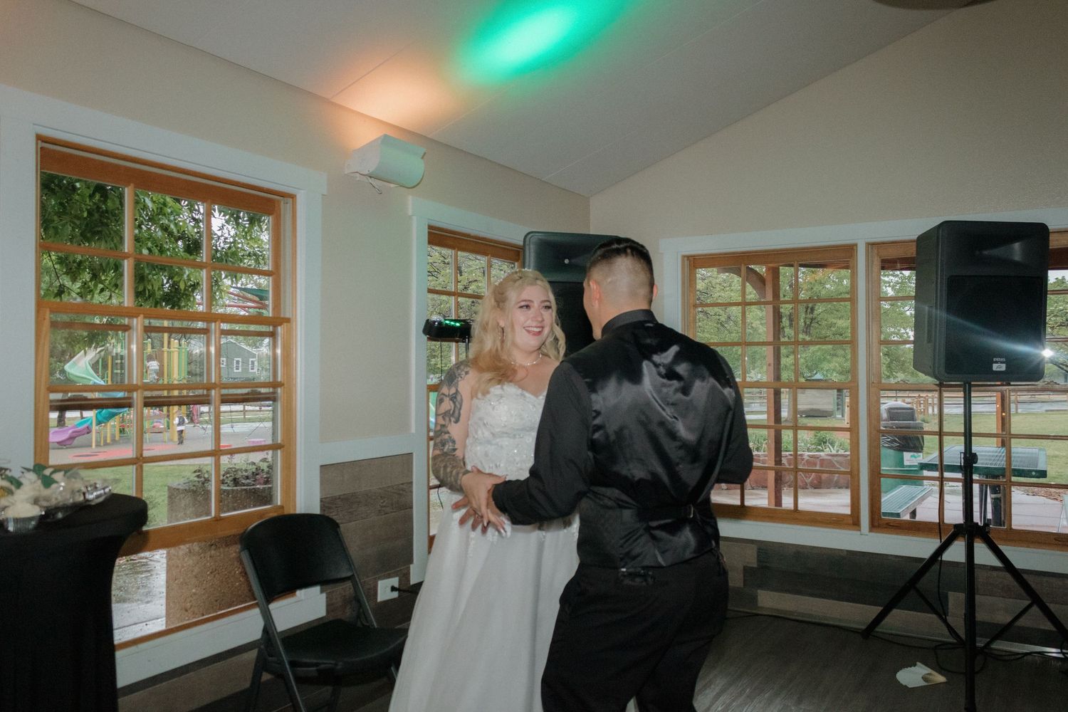 Couple dancing in an indoor venue with large windows and disco lights illuminating the space.