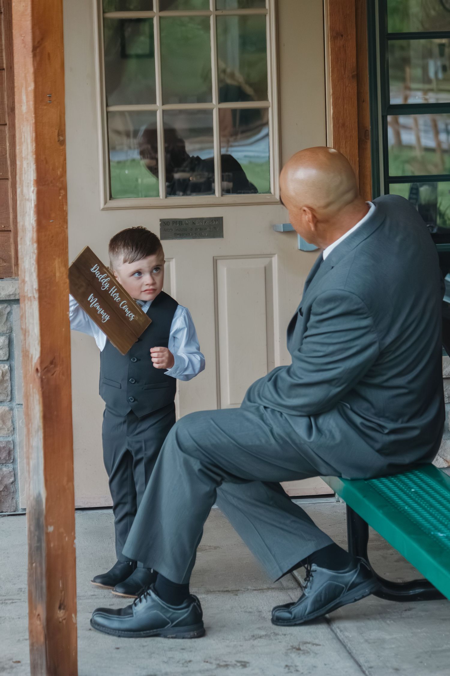 A touching moment between a young ring bearer and wedding guest on a covered porch.