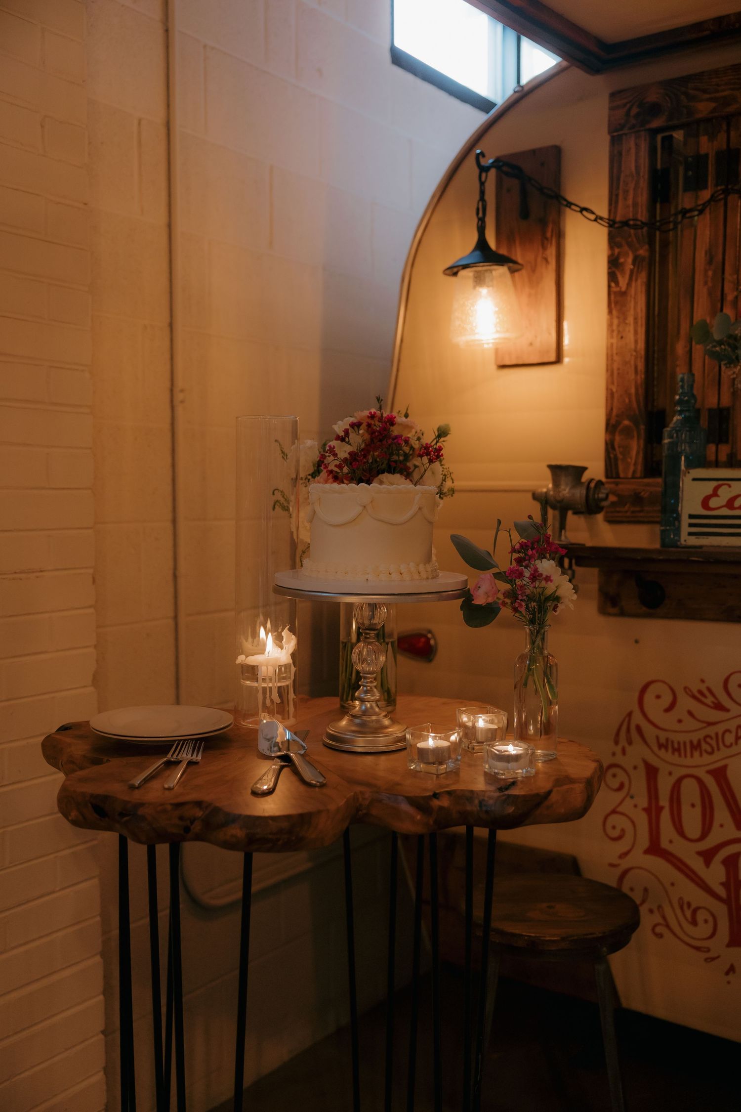 Rustic wedding cake display on live edge wood table with candles and floral accents.