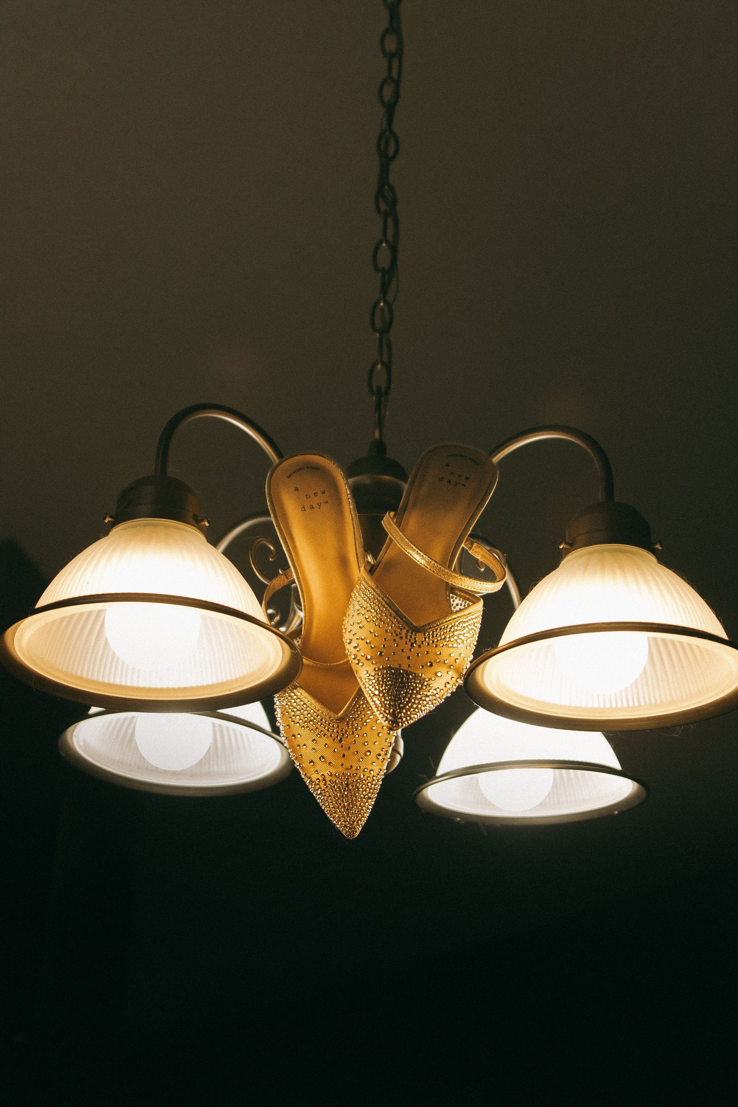 A series of illuminated pendant lamps with glass shades and metallic accents hanging from chains in a dark room.