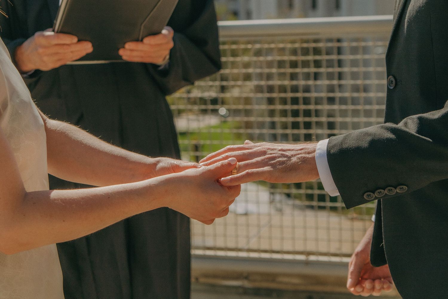Detail shots of hands holding wedding ceremony papers outdoors.