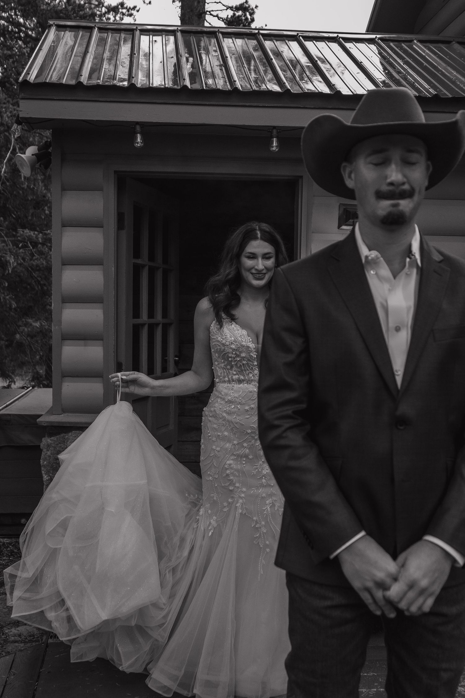 A black and white first look moment outside a rustic cabin.