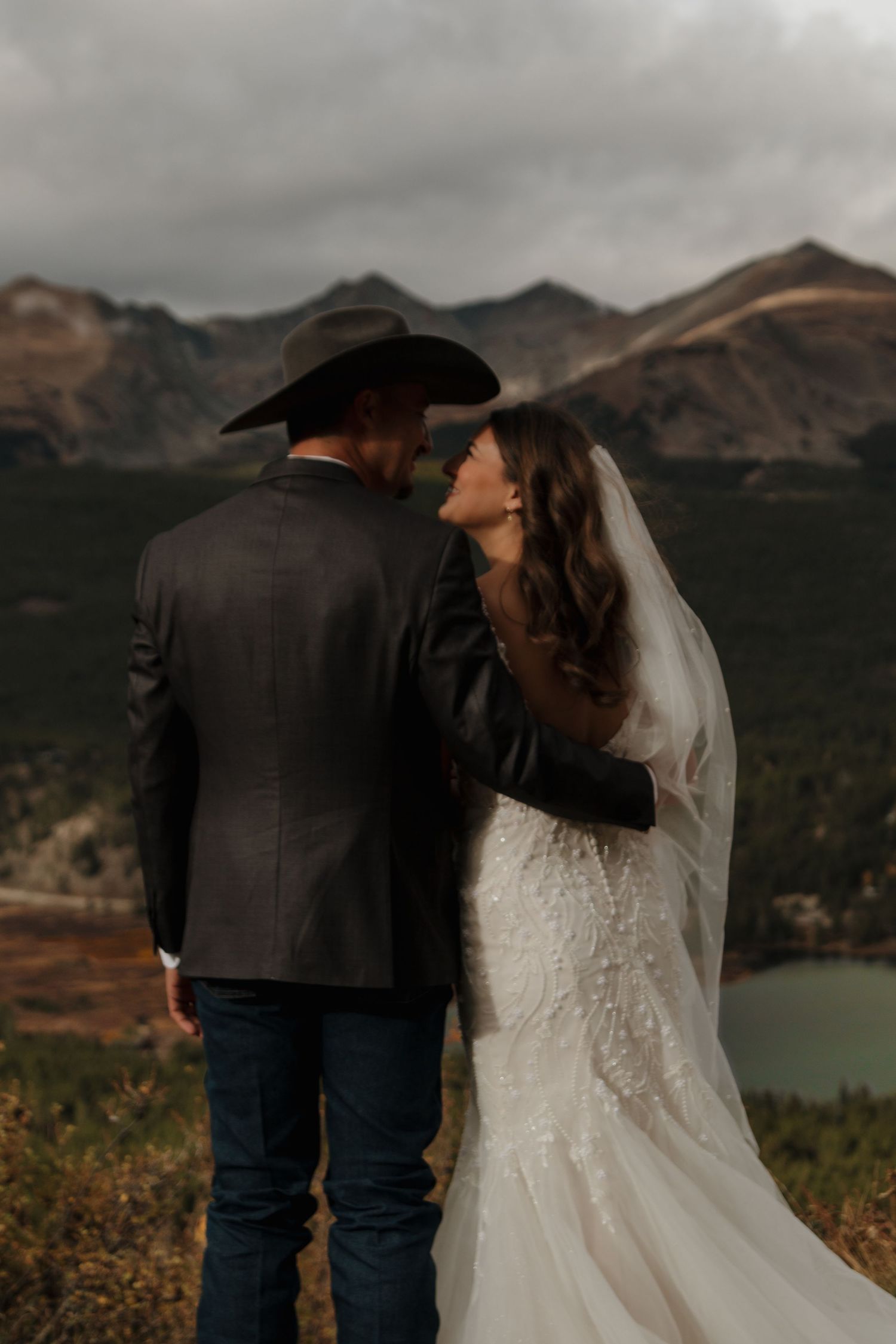 A couple shares an intimate moment against a dramatic mountain landscape at their wedding.