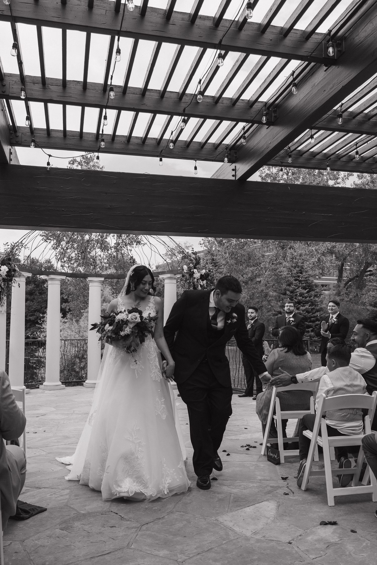 Newlyweds share a kiss while walking back down the aisle after their outdoor wedding ceremony.